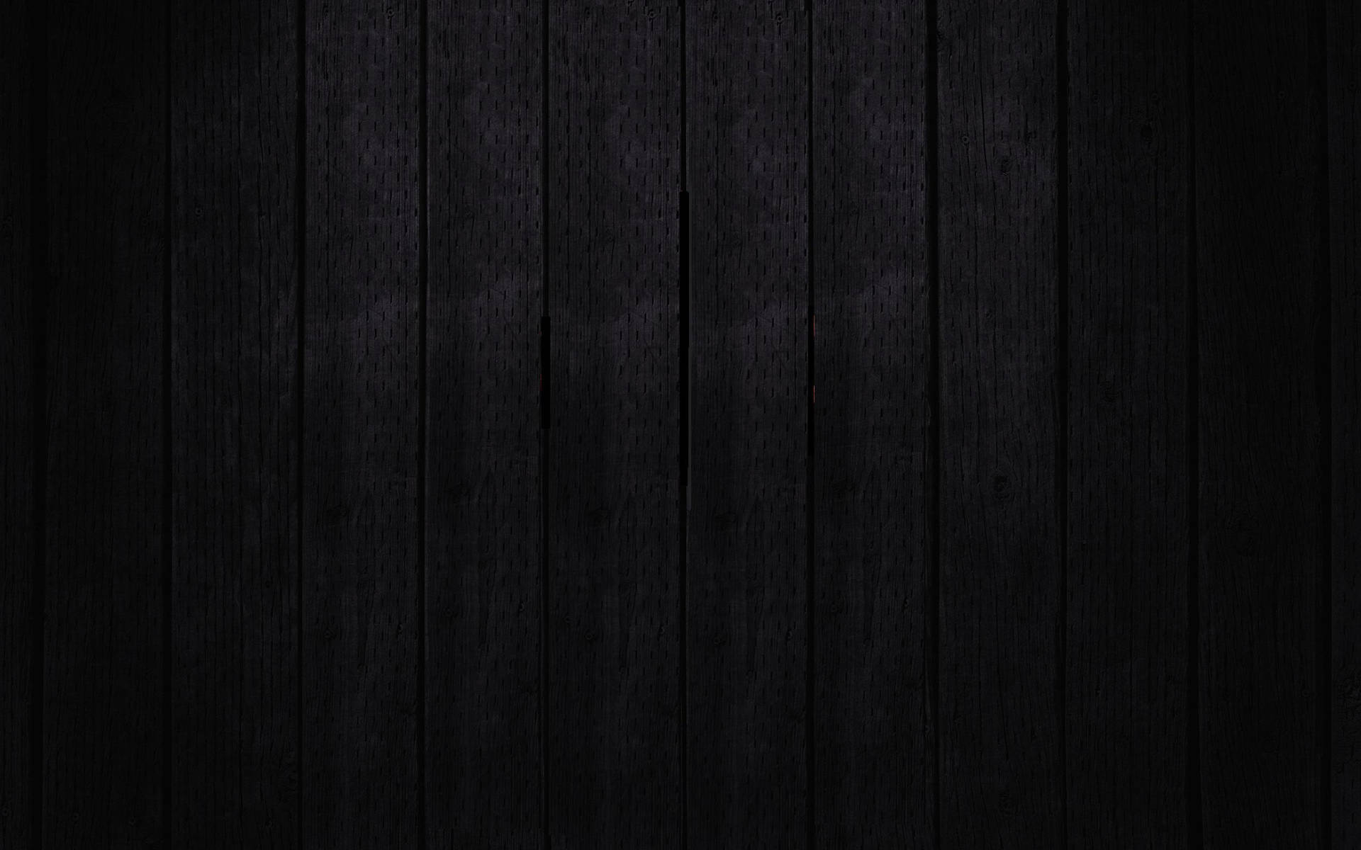 Dark black wooden fence with a rough surface, aligned vertically
