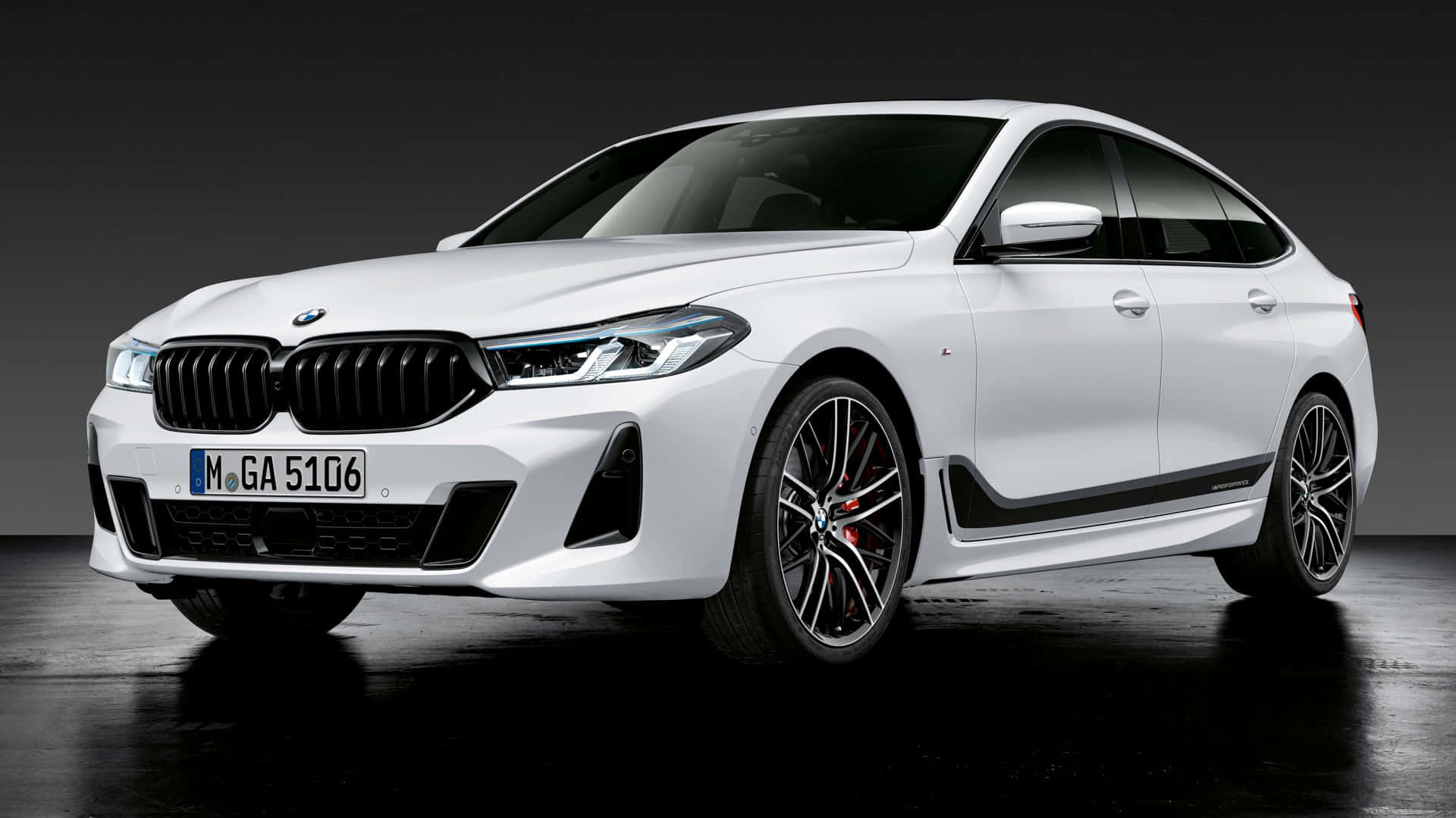 1080p M系列背景：亮面白BMW 6系 壁紙 — 一輛時尚的白色BMW 5系Gran Coupe，帶有黑色飾件和紅色制動卡鉗，在戲劇性燈光下矗立在深色工作室地板上。