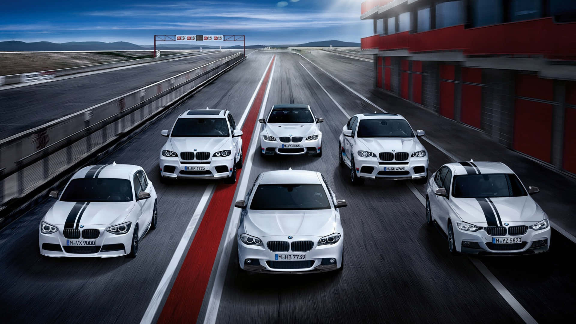 1080p M系列背景：多款白色BMW M系列車 壁紙 — 六輛白色BMW高性能賽車在陰天下的紅白條紋賽道上奔馳。