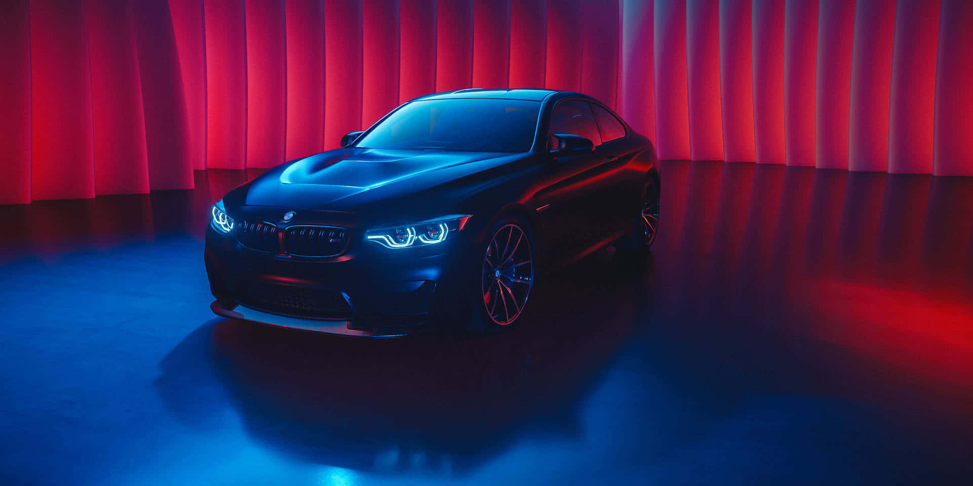 1080p M系列背景：帶藍色燈光的黑色BMW M4 壁紙 — 一輛時尚的黑色BMW跑車在戲劇性的紅色和藍色工作室燈光下，以窗簾為背景閃耀。