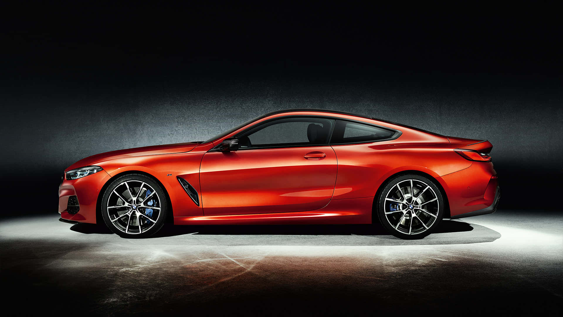 1080p M系列背景：銅色BMW 8系 壁紙 — 一輛時尚的紅色跑車在戲劇性的攝影棚燈光下，以深色紋理背景襯托，閃閃發光。