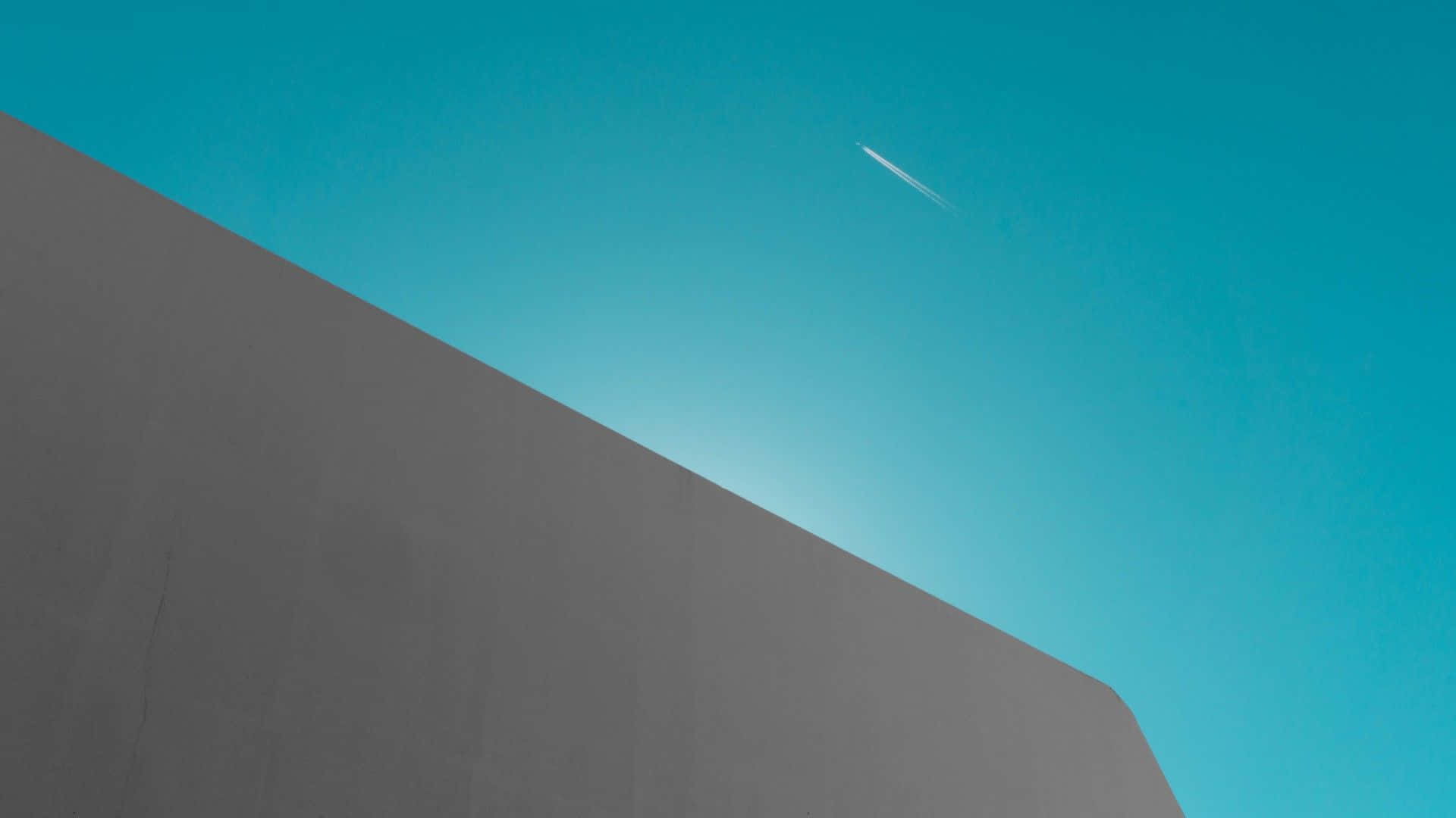 1080p 極簡天空 壁紙 — 一道銳利的灰色混凝土牆對角線切割穿過充滿活力的藍綠色天空，帶有淡淡的飛機尾跡。