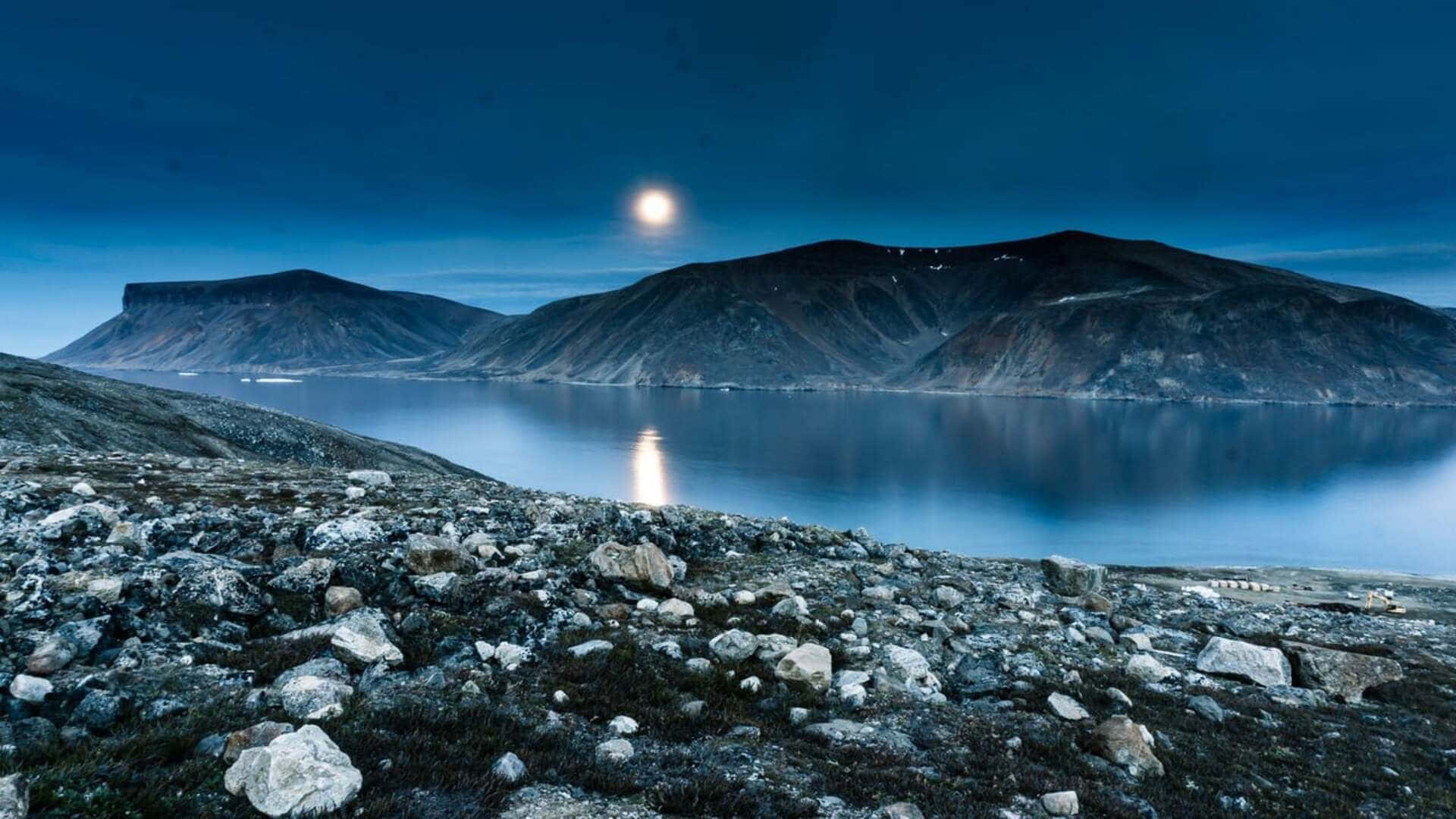 月光照耀著夜晚被岩石山脈環繞的平靜湖泊。