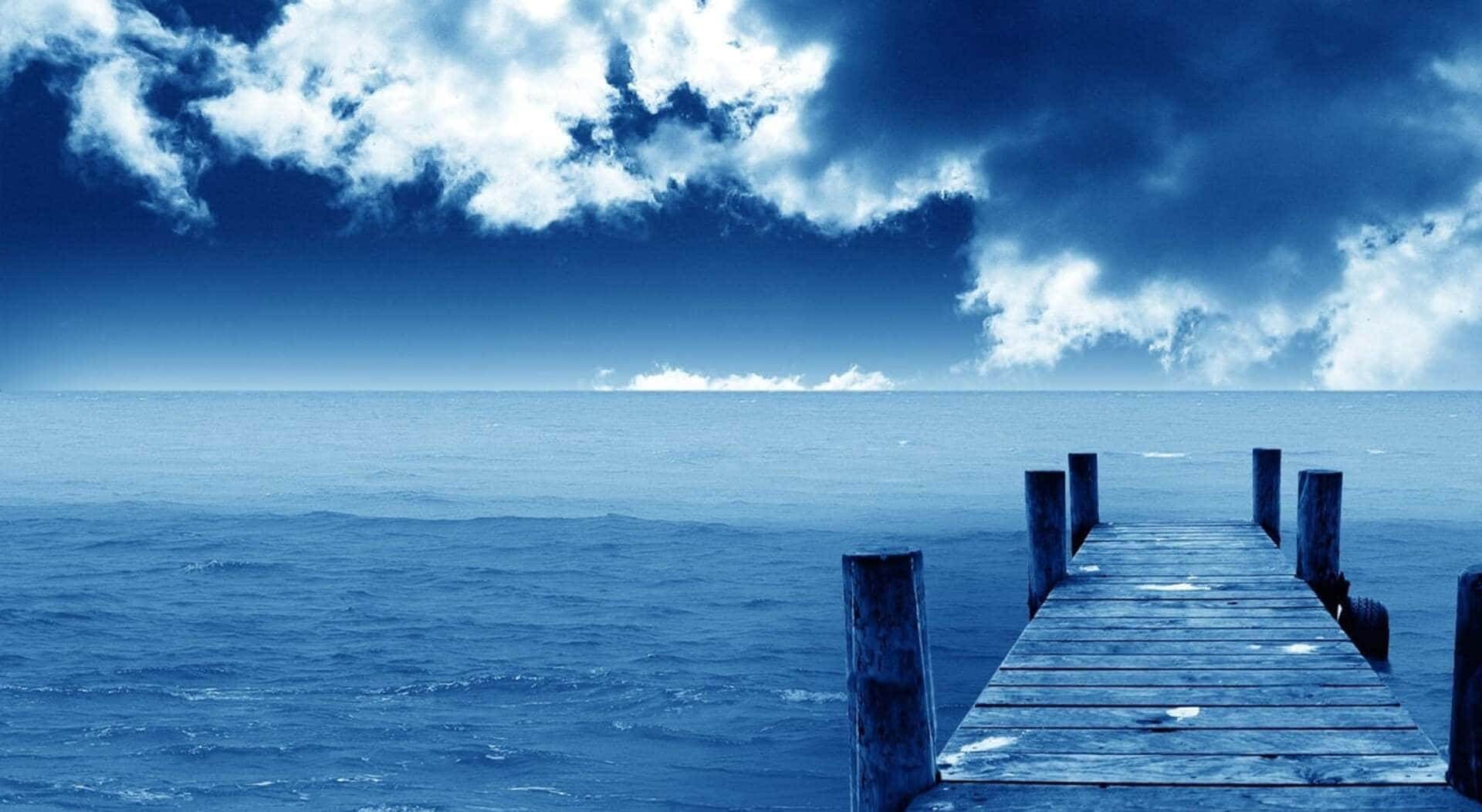 一條長長的木製碼頭在陰天延伸至平靜的藍色海水。