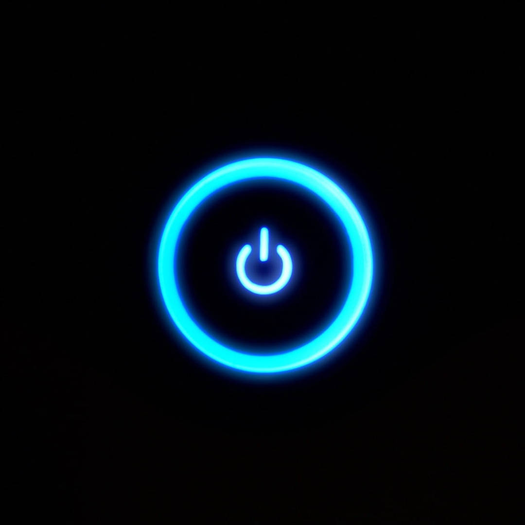  壁紙 — 一個發光的藍色電源按鈕圖標在純黑色背景上柔和地散發光芒。