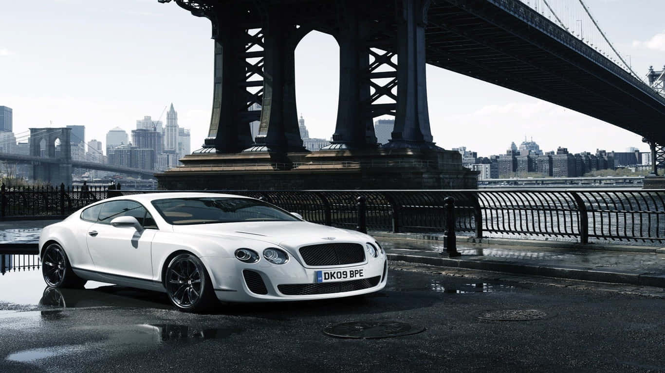 1366x768 宾利背景 — 2010 白色 Bentley Continental Supersports 壁紙 — 一架時尚的白色賓利 Continental GT 停泊在布魯克林橋下，濕漉漉的城市街道上，背景是城市天際線。