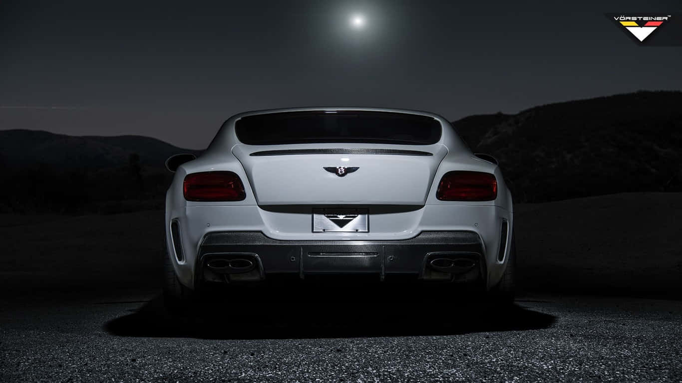 1366x768 2018 白色賓利 Continental GT 後保險桿背景 壁紙 — 一輛時尚的銀色賓利 Continental GT 在夜晚停泊於明亮的月光下，背景是黑暗的山丘。