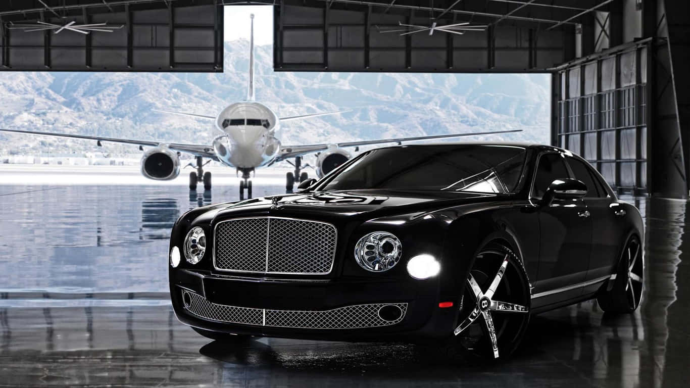 1366x768 宾利背景 — 黑色 2014 Bentley Mulsanne 壁紙 — 一架時尚的黑色賓利轎車在機庫中閃耀，透過敞開的門可以看到私人飛機和雪山。