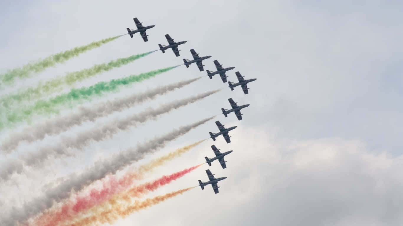 1366x768 巨型客機背景 隊形飛行 壁紙 — 九架戰鬥機以緊密編隊飛越多雲的天空，留下鮮豔的綠色、白色和紅色煙跡。