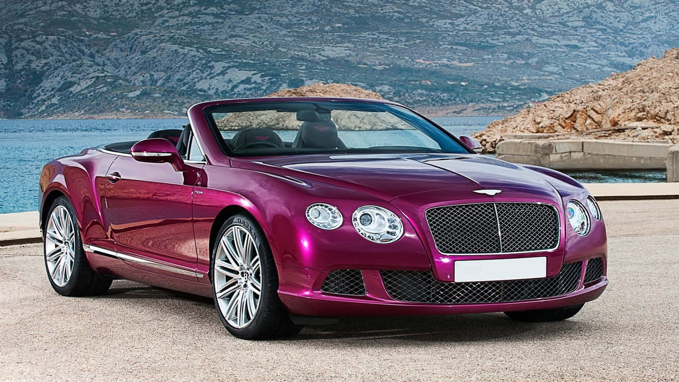 1366x768 紫色 2014 賓利 Continental GT Speed 背景 壁紙 — 一架亮面洋紅色賓利開篷車停泊喺沿海公路，後面有岩石懸崖同藍色海水。