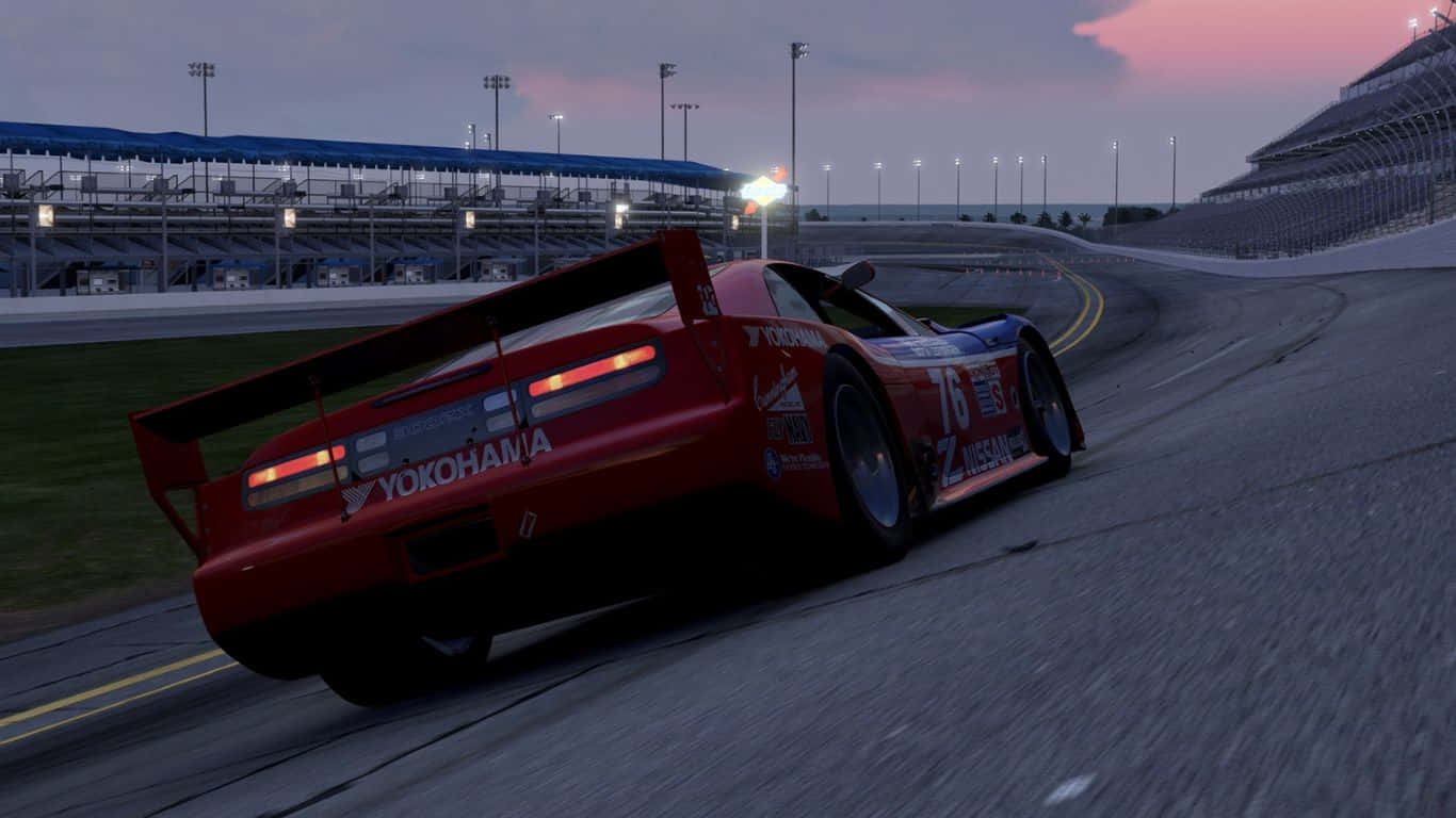 1366x768 解析度 Project Cars 2 動感世界背景 壁紙 — 一輛帶有橫濱品牌標誌的紅色賽車在黃昏時分於體育場燈光下在賽道上飄移。