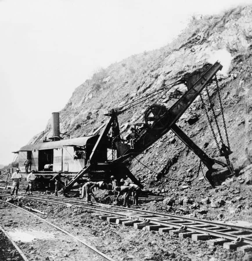 1910年巴拿馬運河古風照片 壁紙 — 歷史黑白照片，工人操作蒸汽動力鏟車在穿過岩石山坡的鐵路軌道上。