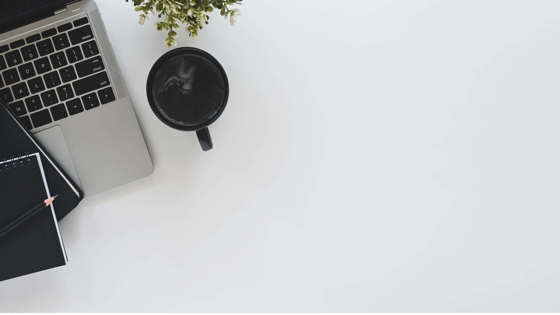 1920 X 1080 桌布 壁紙 — 從上方俯瞰簡約白色書桌，配有銀色手提電腦、黑色馬克杯和小型綠色植物。