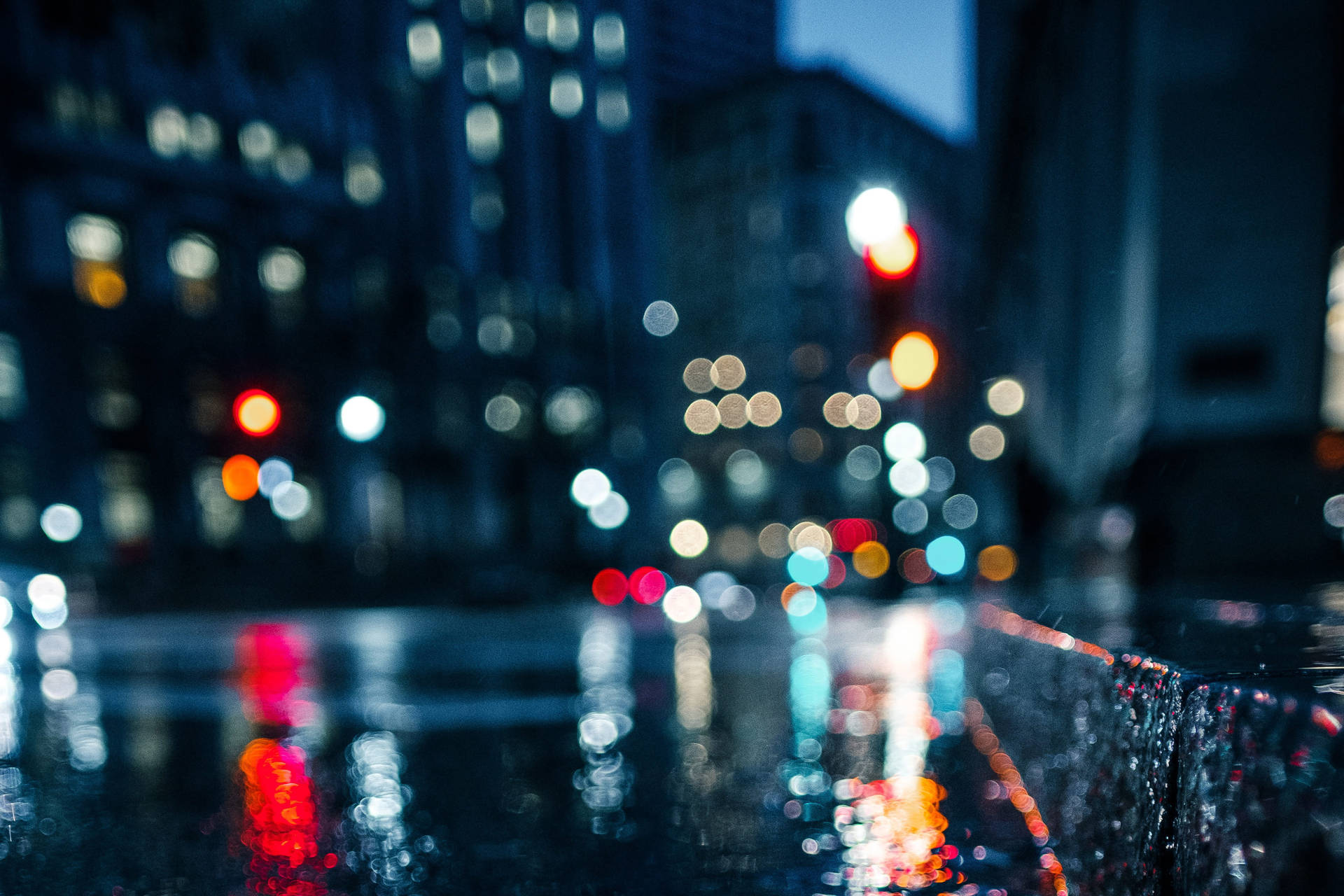 雨滴將城市燈光模糊成發光球體，在夜間濕漉漉的人行道上反射。