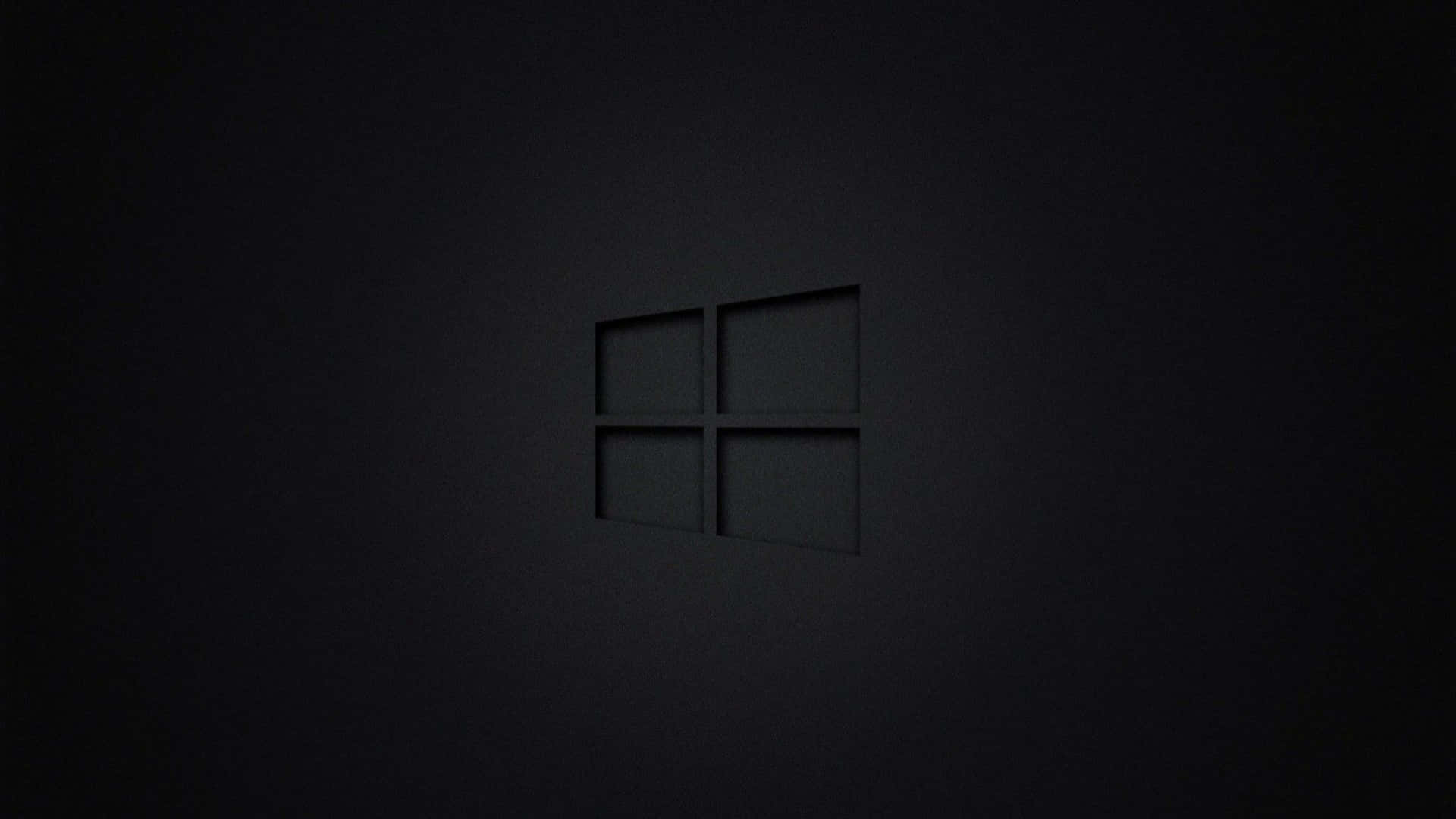 黑色抽象背景 壁紙 — 一個極簡的深灰色Windows標誌，在柔和環境光下微妙地壓印在帶紋理的黑色牆壁上。