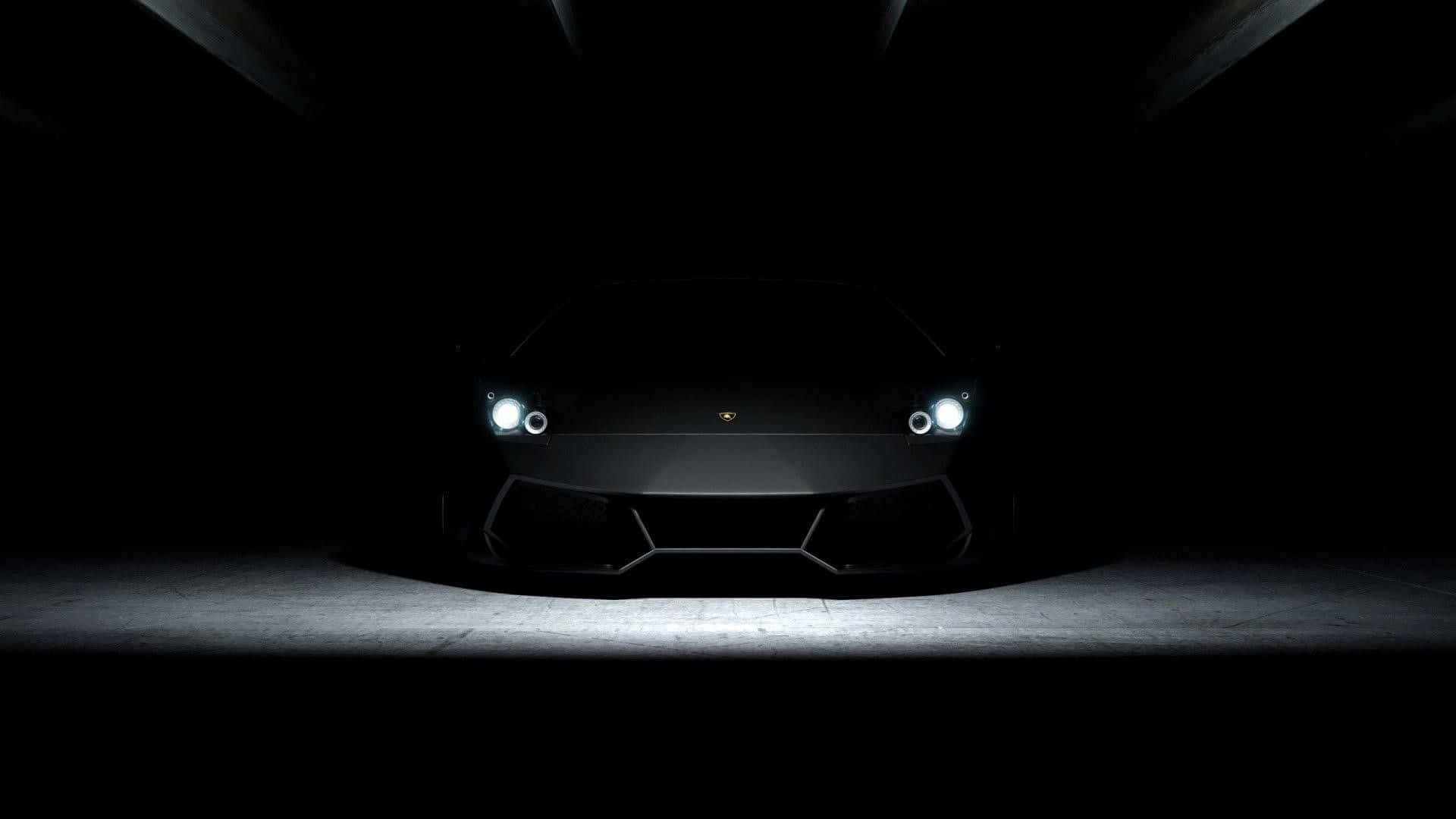 1920x1080 黑色 Lamborghini Aventador 車頭 壁紙 — 一輛時尚的黑色林寶堅尼跑車在黑暗隧道中，在戲劇性的聚光燈下閃耀，車頭燈發光。