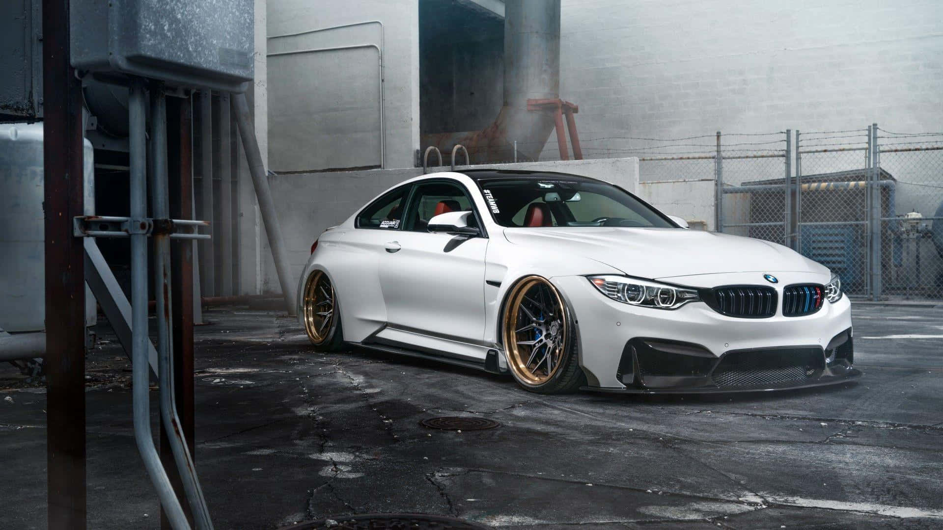白色BMW M4雙門轎跑車配金色輪圈停放在工業車庫。
