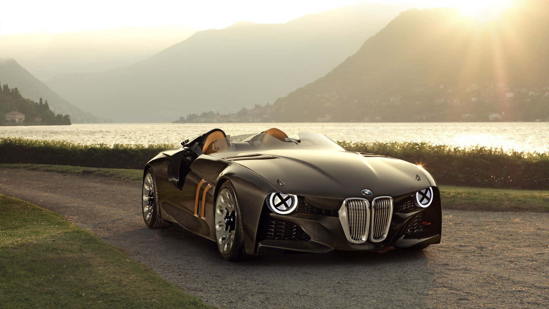 日落時分，一輛黑色BMW概念車停在湖邊，背後有山脈。