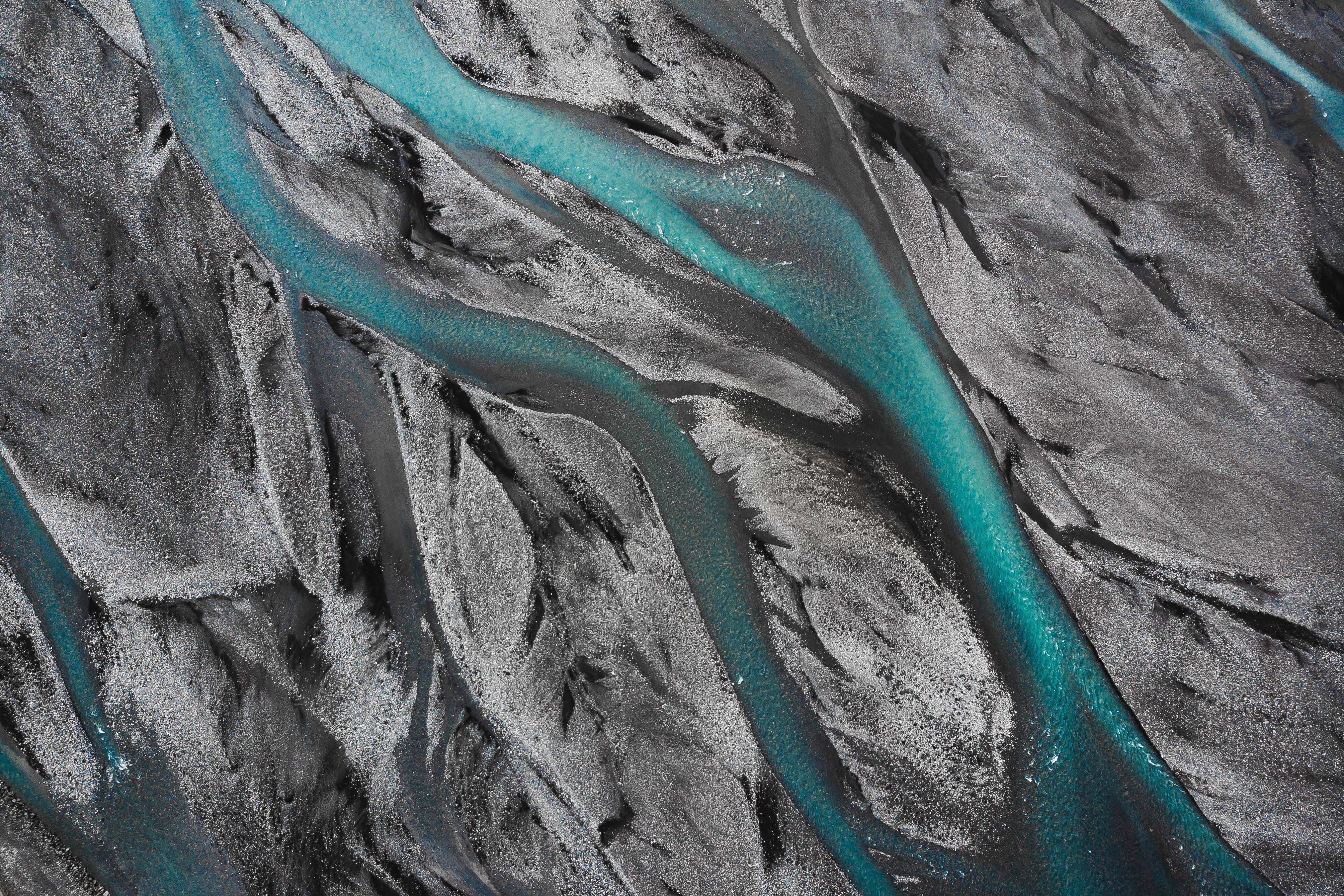 1920x1080 HD 自然風景：冰島背景 壁紙 — 鳥瞰圖，鮮豔的藍綠色河流蜿蜒穿過 stark 黑色火山沙，形成超現實的自然圖案。