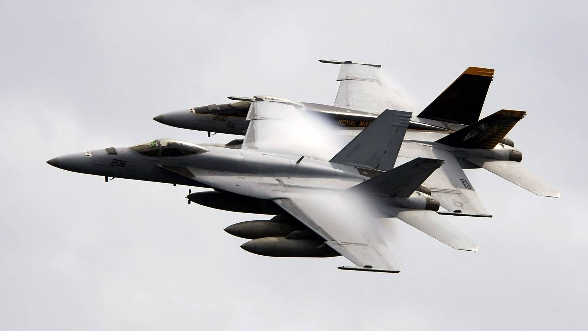 1920x1080 超級大黃蜂戰鬥機 壁紙 — 兩架英國皇家海軍戰鬥機在蒼白的陰天緊密編隊飛行，留下蒸汽痕跡。