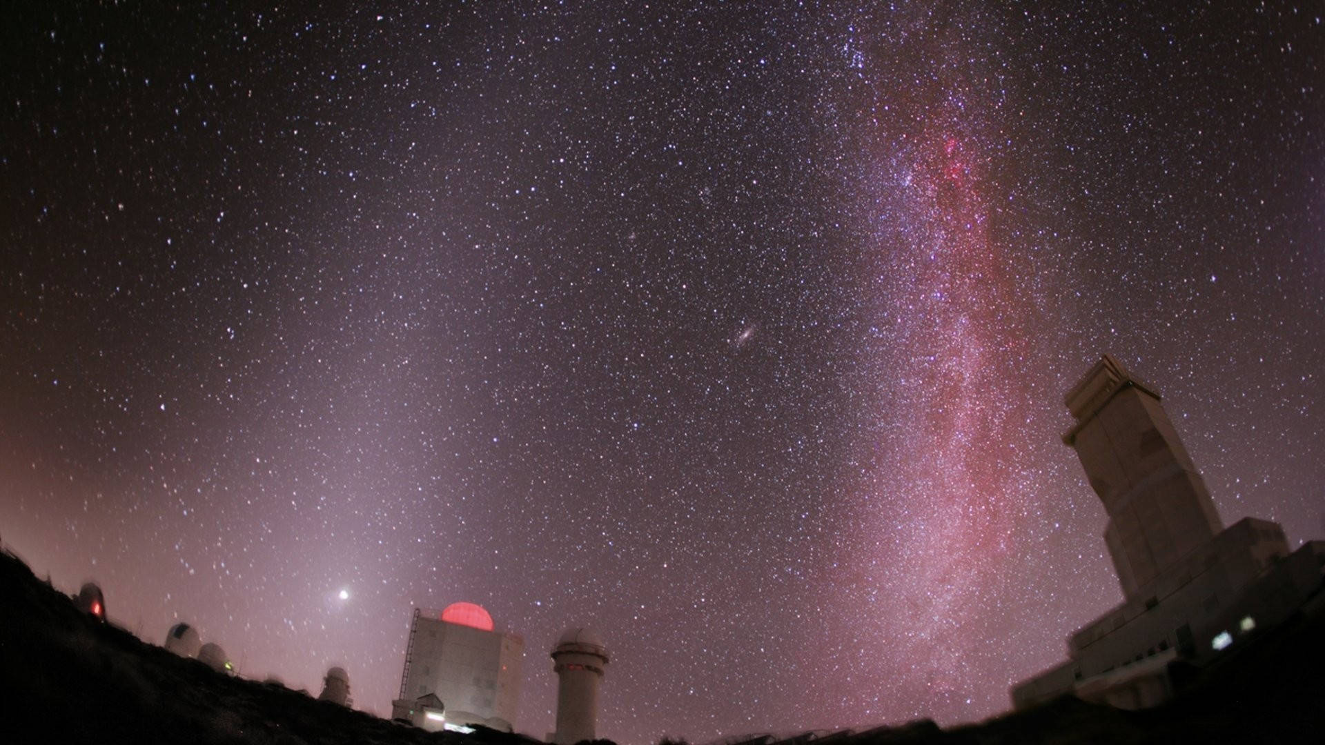 1920x1080 高清自然泰德天文台夜空 壁紙 — 繁星點點的夜空，充滿活力的粉紫色銀河在黑暗山坡上的天文台圓頂上方拱起。