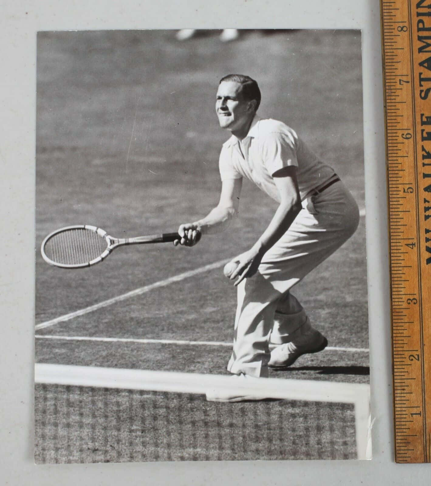 德國網球選手戈特弗里德·馮·克拉姆，1937年照片 壁紙 — 一張復古黑白照片，顯示一名男性網球運動員在草地場上揮拍中，旁邊放著一把尺。
