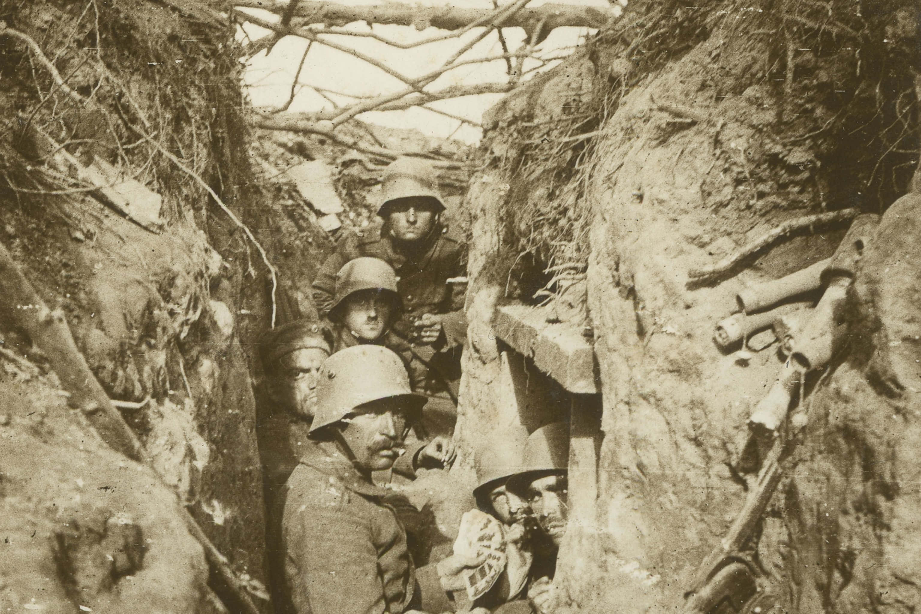1945年硫磺島戰役 壁紙 — 戴頭盔的士兵擠在泥濘的戰壕中，周圍是泥土和折斷的樹枝。