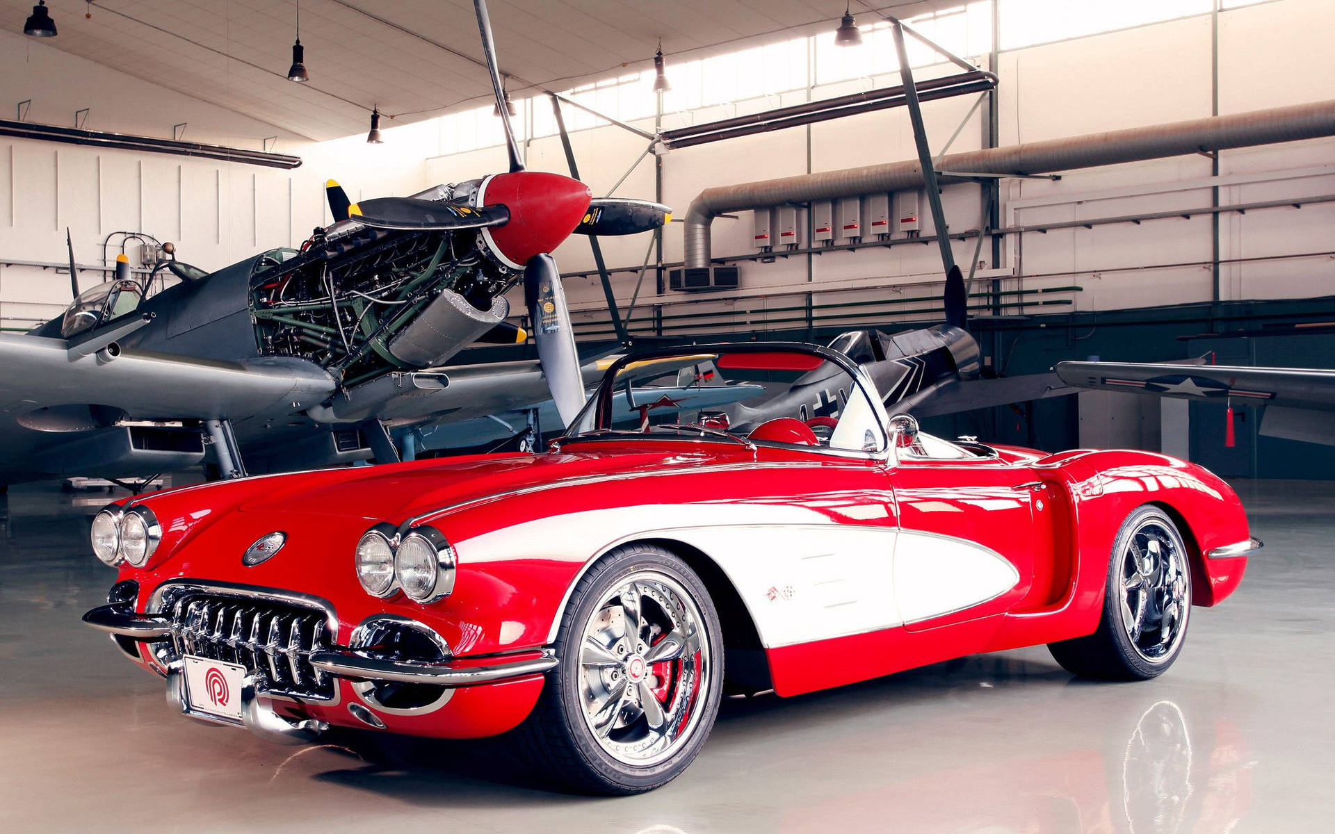 機庫內復古飛機旁邊的紅白經典Corvette開篷車。