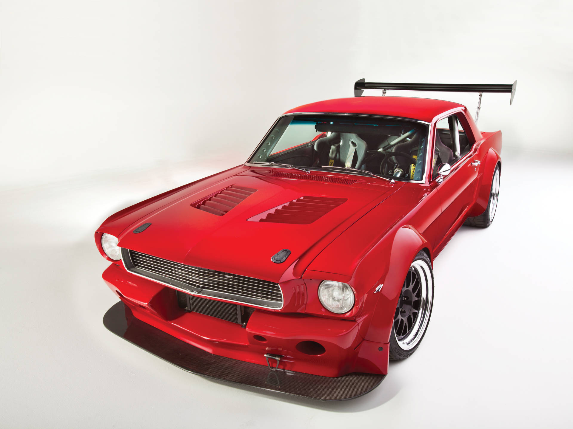 白色工作室中帶有賽車翼的紅色定製肌肉車