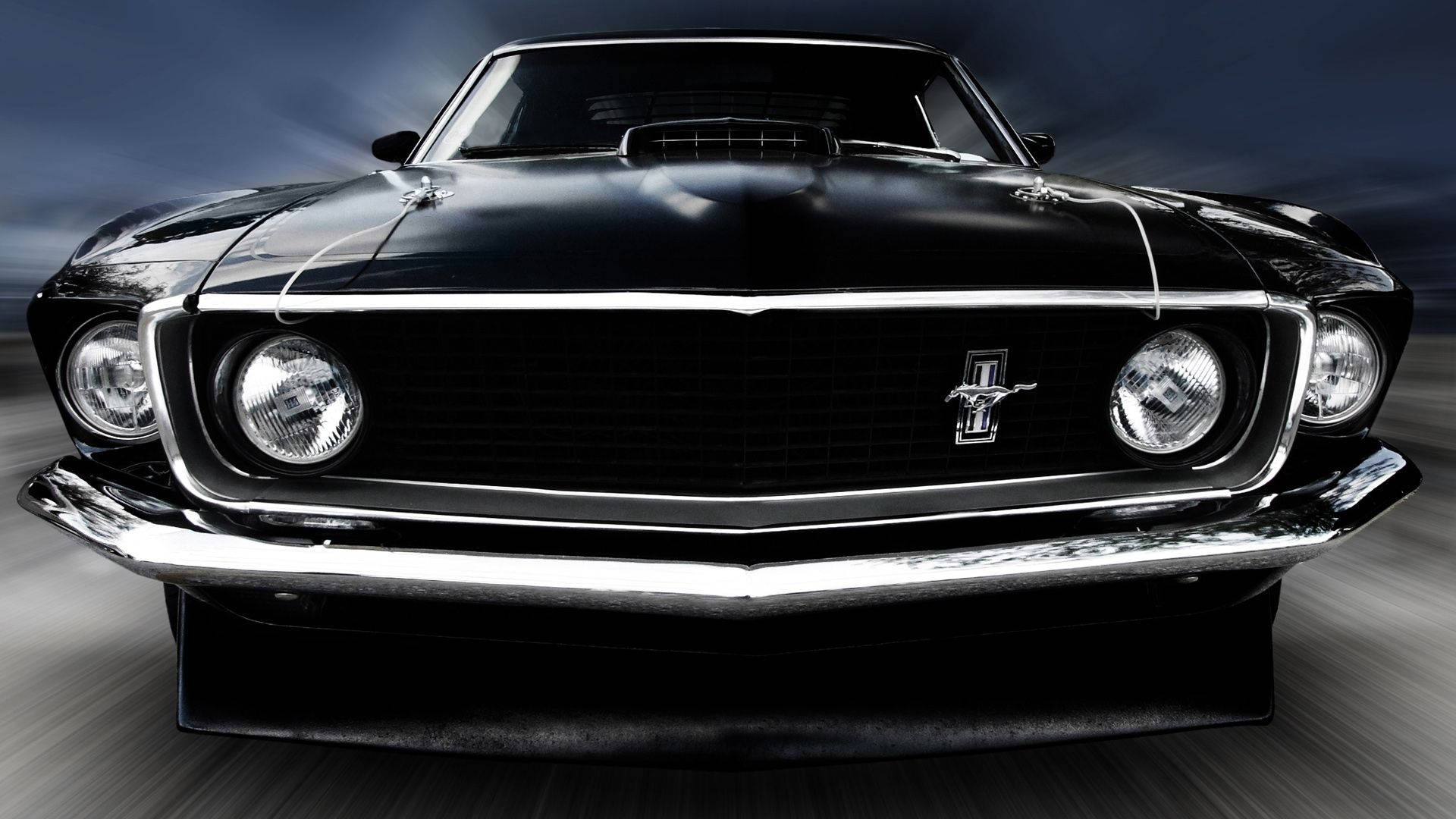 黑色1969年福特野馬經典車 壁紙 — 一輛帶有鍍鉻裝飾的時尚黑色經典野馬肌肉車在黑暗暴風雨的天空下疾馳。