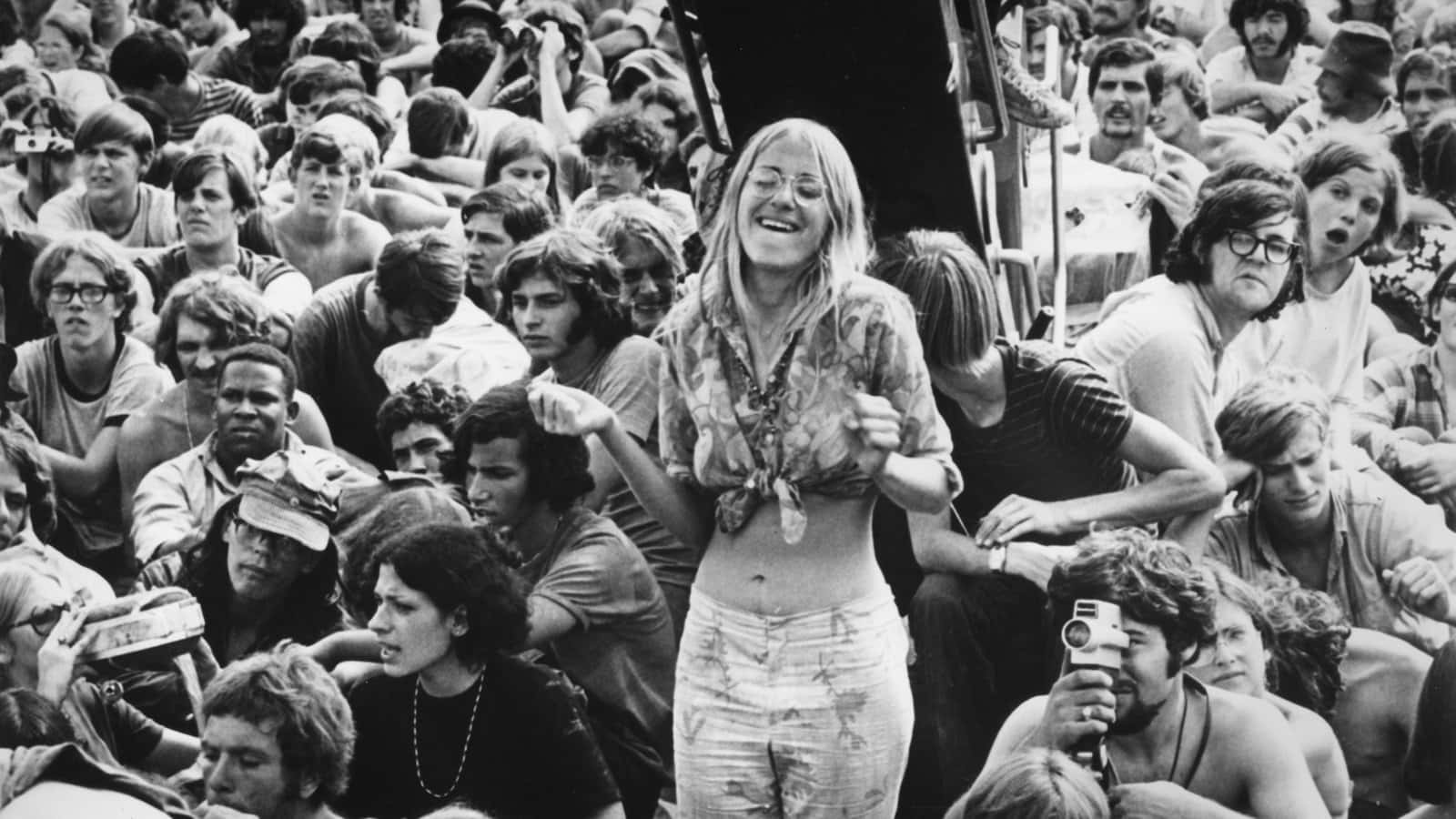 一位微笑的女士在1970年代的戶外音樂會上，被人群包圍著跳舞。