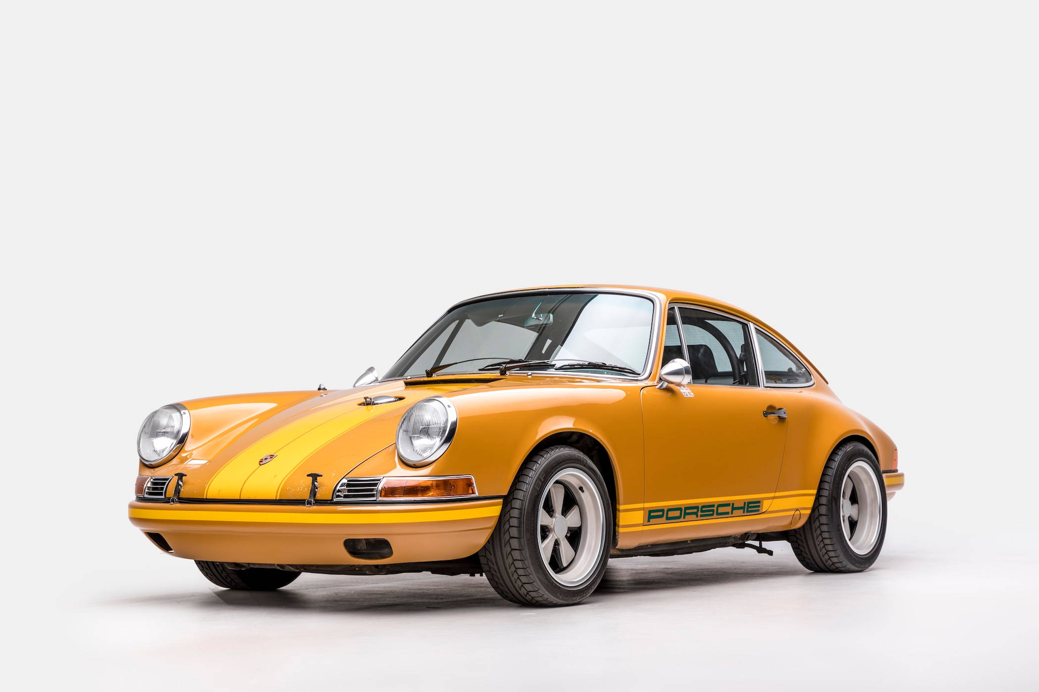 1970年Singer保時捷912 壁紙 — 一輛充滿活力的橙色復古保時捷911跑車，帶有黑色賽車條紋和白色側壁輪胎，擺放在乾淨的白色工作室背景前。