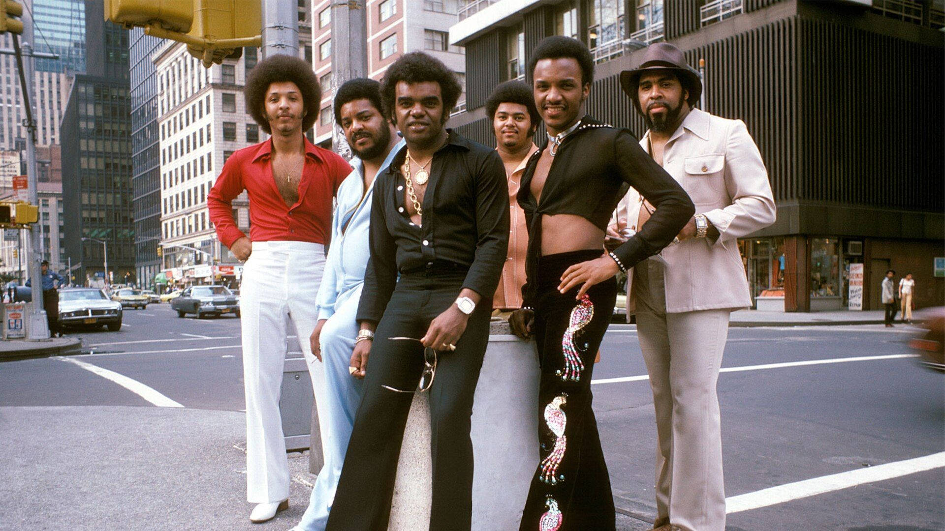 1975年 Isley Brothers 街頭經典肖像 壁紙 — 六位時尚男士穿著大膽的1970年代時尚，在繁華的城市街角自信地擺姿勢。