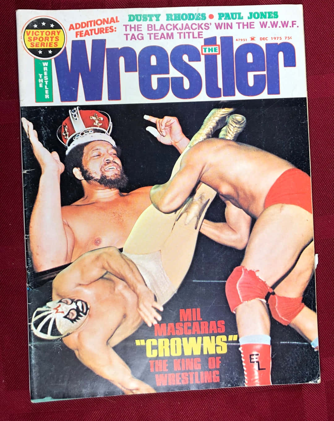 Victory Sports Series Ernie Ladd 壁紙 — 1975年復古摔角雜誌封面顯示達斯蒂·羅茲和保羅·瓊斯與一名蒙面摔角手以戲劇性姿勢慶祝雙打冠軍勝利。