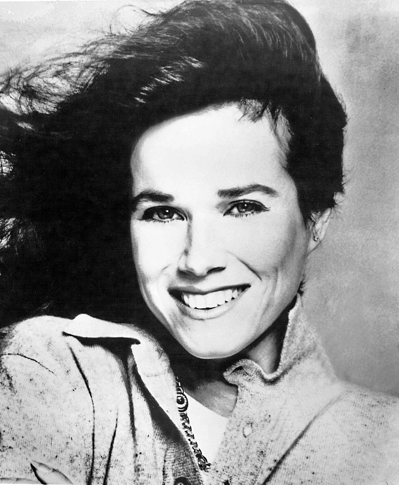 一位微笑女士在工作室肖像中，頭髮被風吹動。