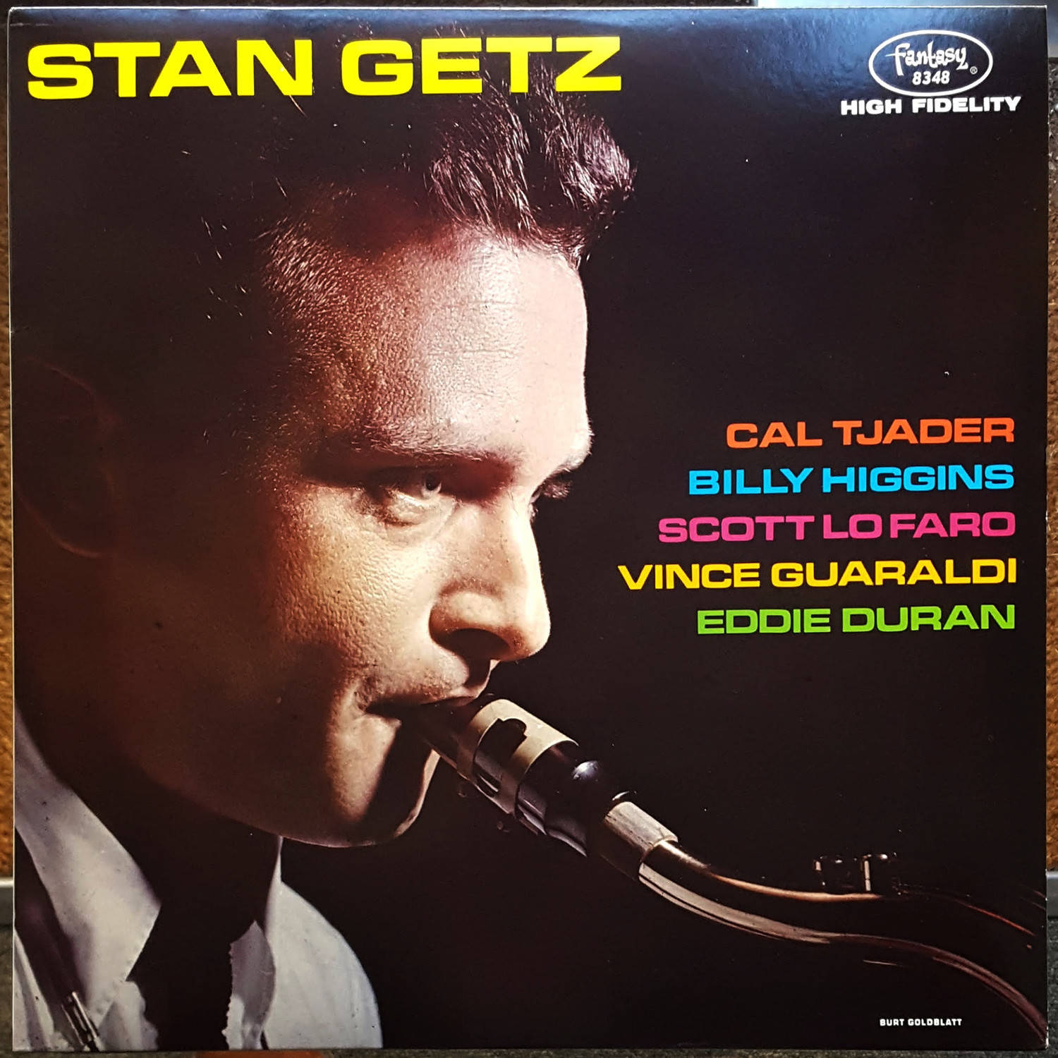 斯坦·蓋茲1990年CD專輯封面 壁紙 — 爵士色士風手 Stan Getz 的側面特寫，在深色背景上帶有彩色文字，對著復古咪高峰演奏。