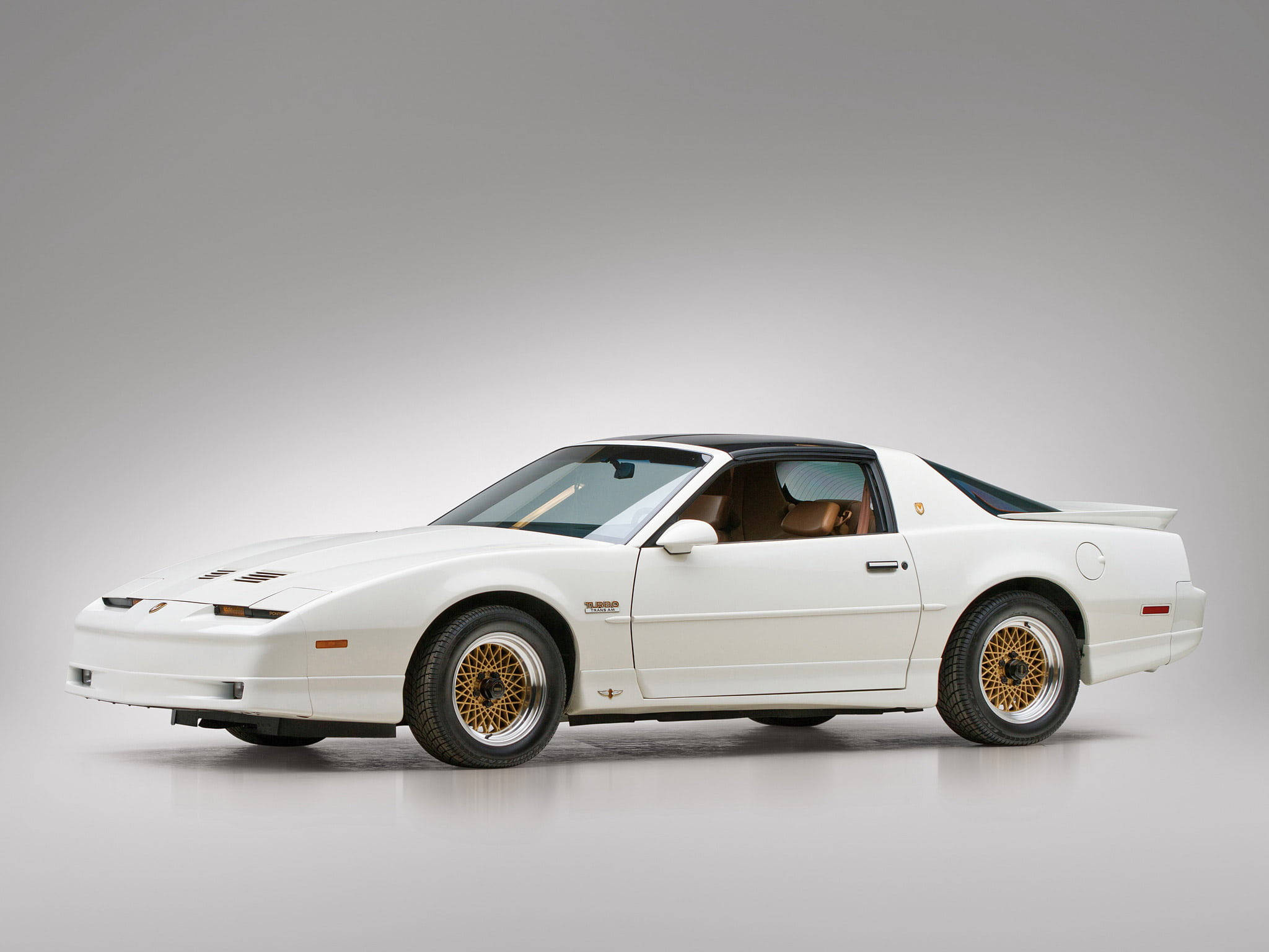 1992龐蒂克火鳥GTA 壁紙 — 一架純白色的Pontiac Fiero Turbo配金色輪圈，在極簡風格的攝影棚中展示其80年代跑車的流線設計。