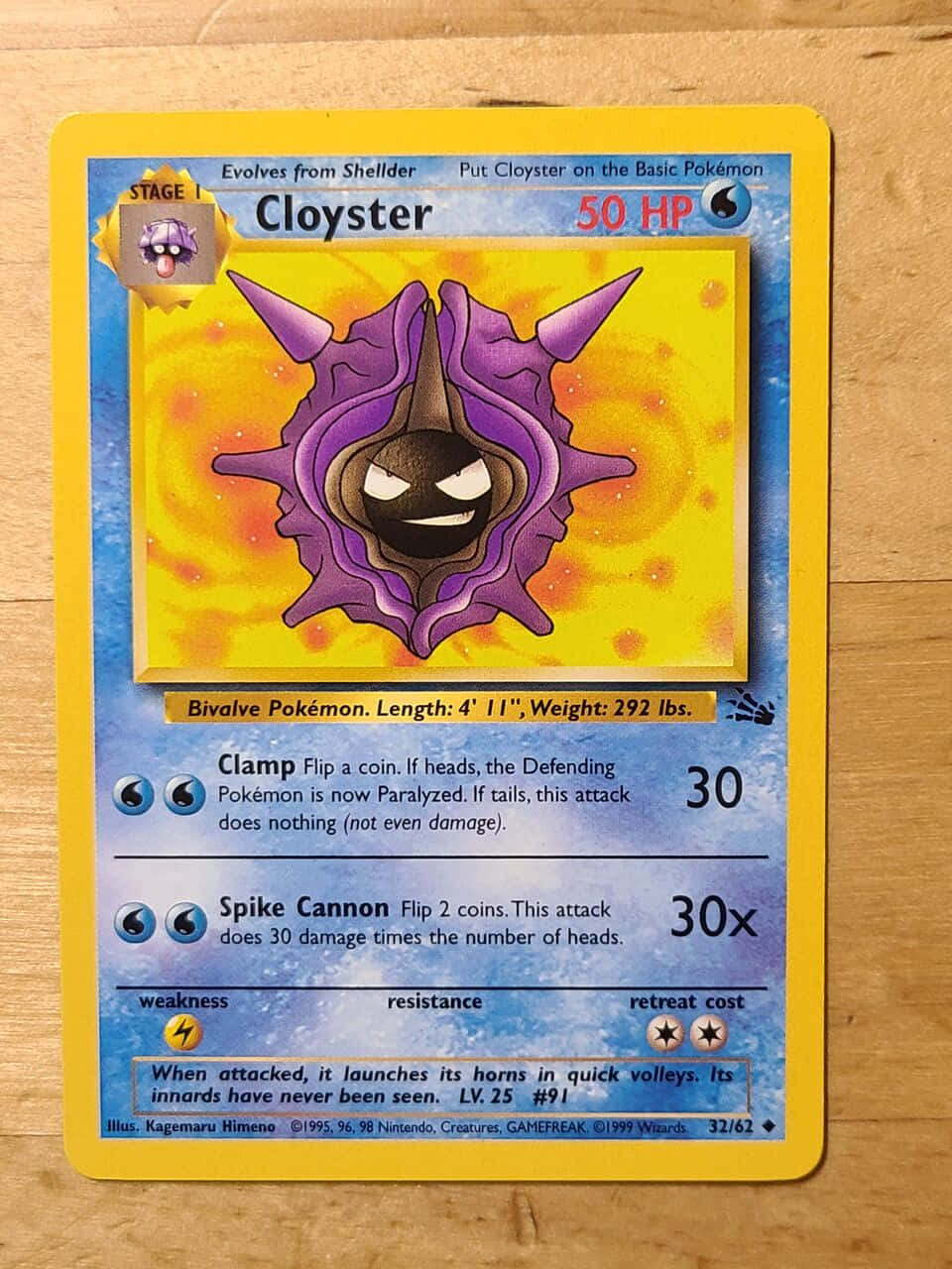 1999 年罕見 Cloyster 卡牌 壁紙 — 一張復古寶可夢卡， featuring 大舌貝，有紫色角和黑色臉，背景是黃橙色漩渦，放在木質表面上。