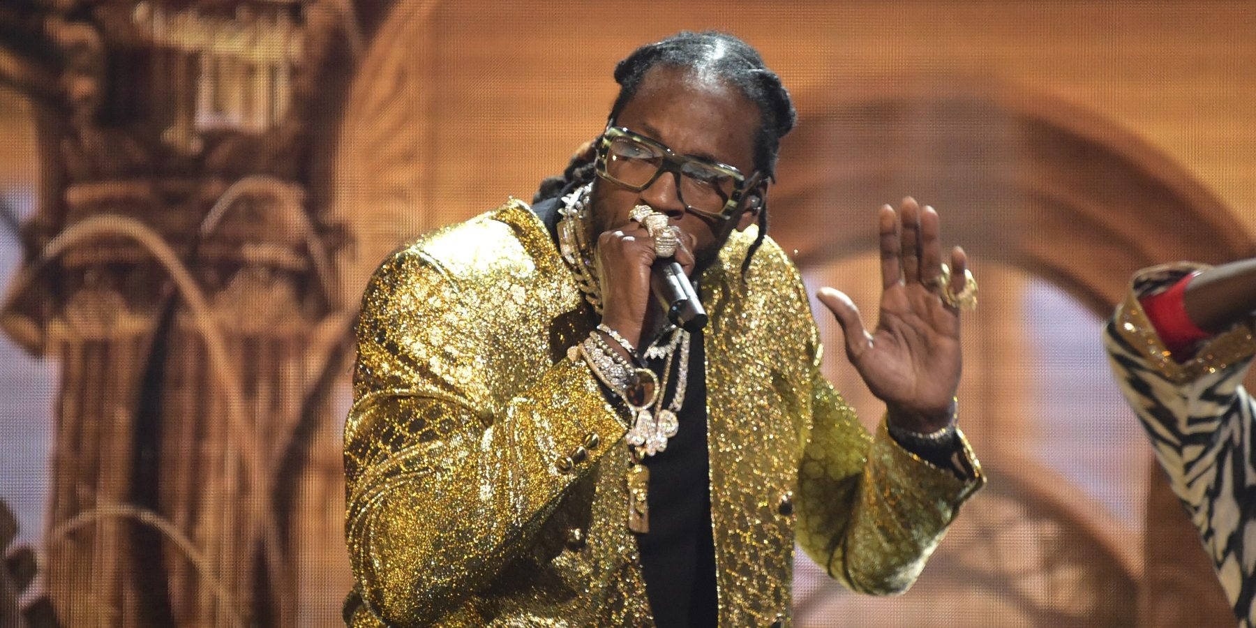 Snoop Dogg 穿著金色外套和眼鏡在舞台上唱歌。