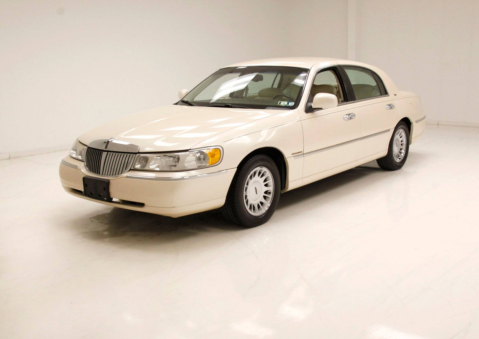 2002 林肯 Town Car 攝影 壁紙 — 一輛純淨的奶油色林肯城市轎車在明亮的攝影棚燈光下，在無縫的白色地板上閃閃發光。