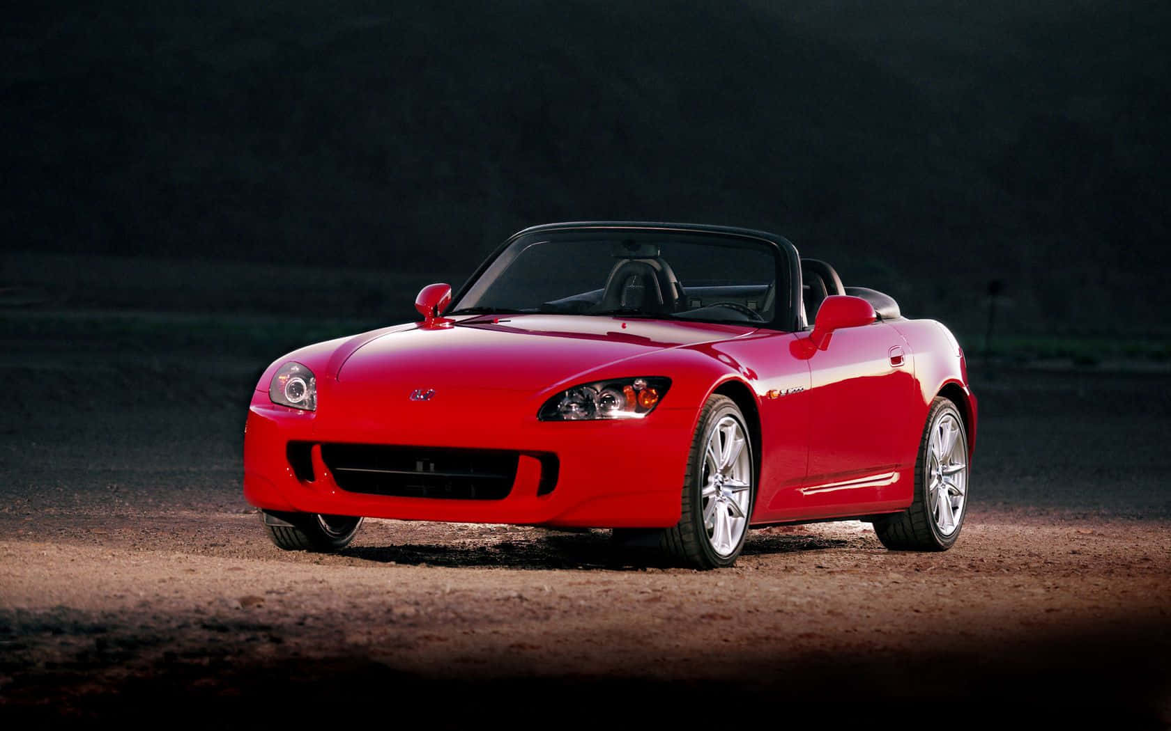 2004款本田S2000紅色敞篷車 壁紙 — 一輛鮮紅色的敞篷跑車在黃昏的泥路上，在戲劇性的燈光下閃閃發光。