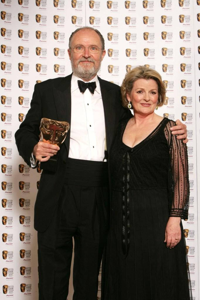 2007年BAFTA頒獎典禮：吉姆·布勞德本特與布蘭達·布蕾頓 壁紙 — 一名身穿黑色正裝的男士和女士在BAFTA頒獎典禮上一起擺姿勢，男士手持金色獎盃，背景為品牌背景。