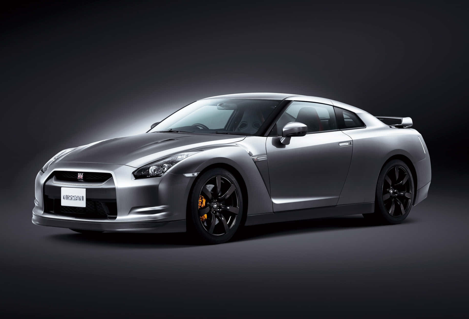 銀色日產GT-R跑車在攝影棚燈光下，帶有黑色飾件和橙色制動卡鉗。