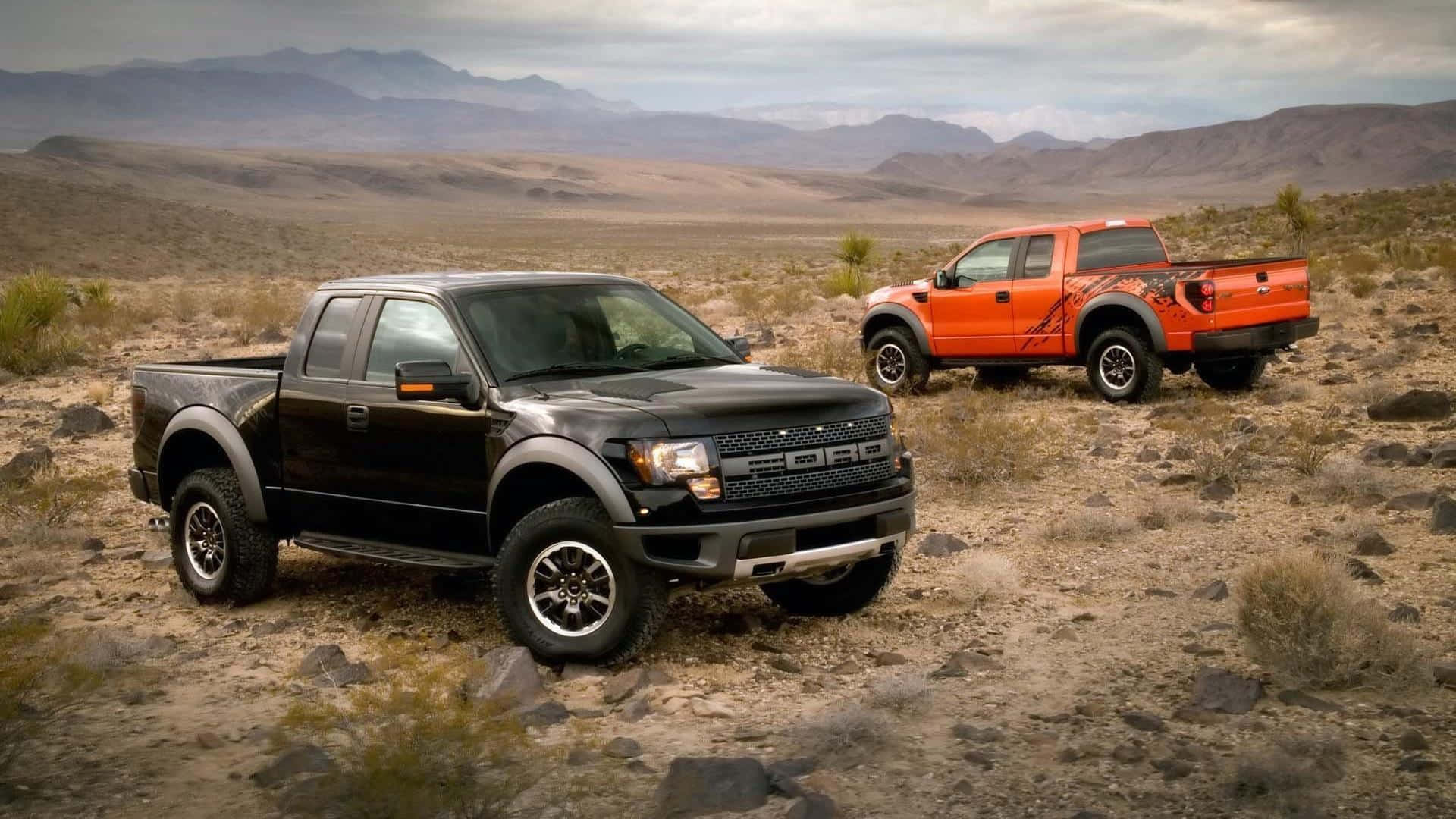 2010款黑色福特F-150 SVT Raptor皮卡 壁紙 — 兩輛堅固的福特黑色和橙色卡車停在岩石沙漠地形上，遠處有山脈，天空多雲。