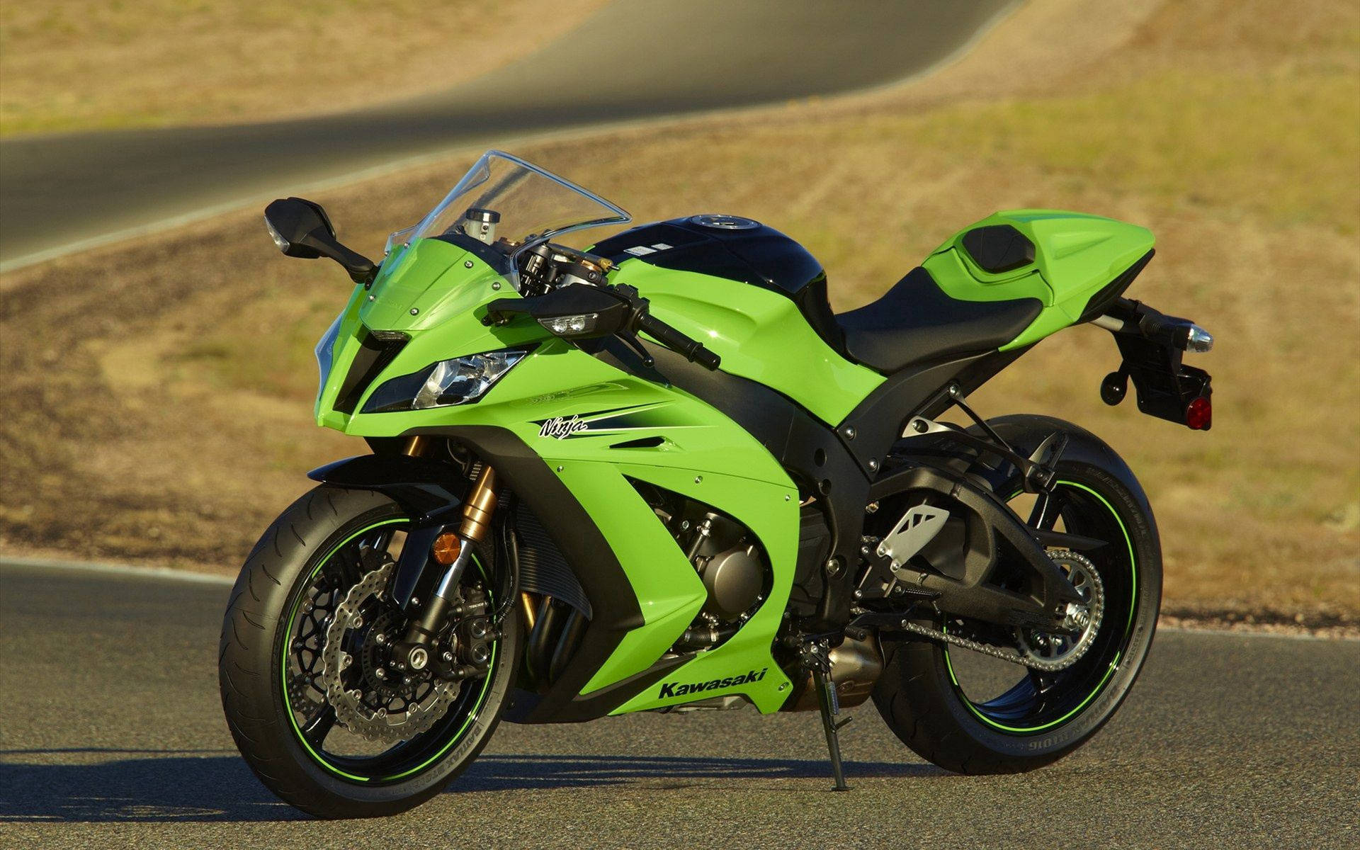 綠色Kawasaki Ninja電單車停泊在日落時分的蜿蜒道路上。