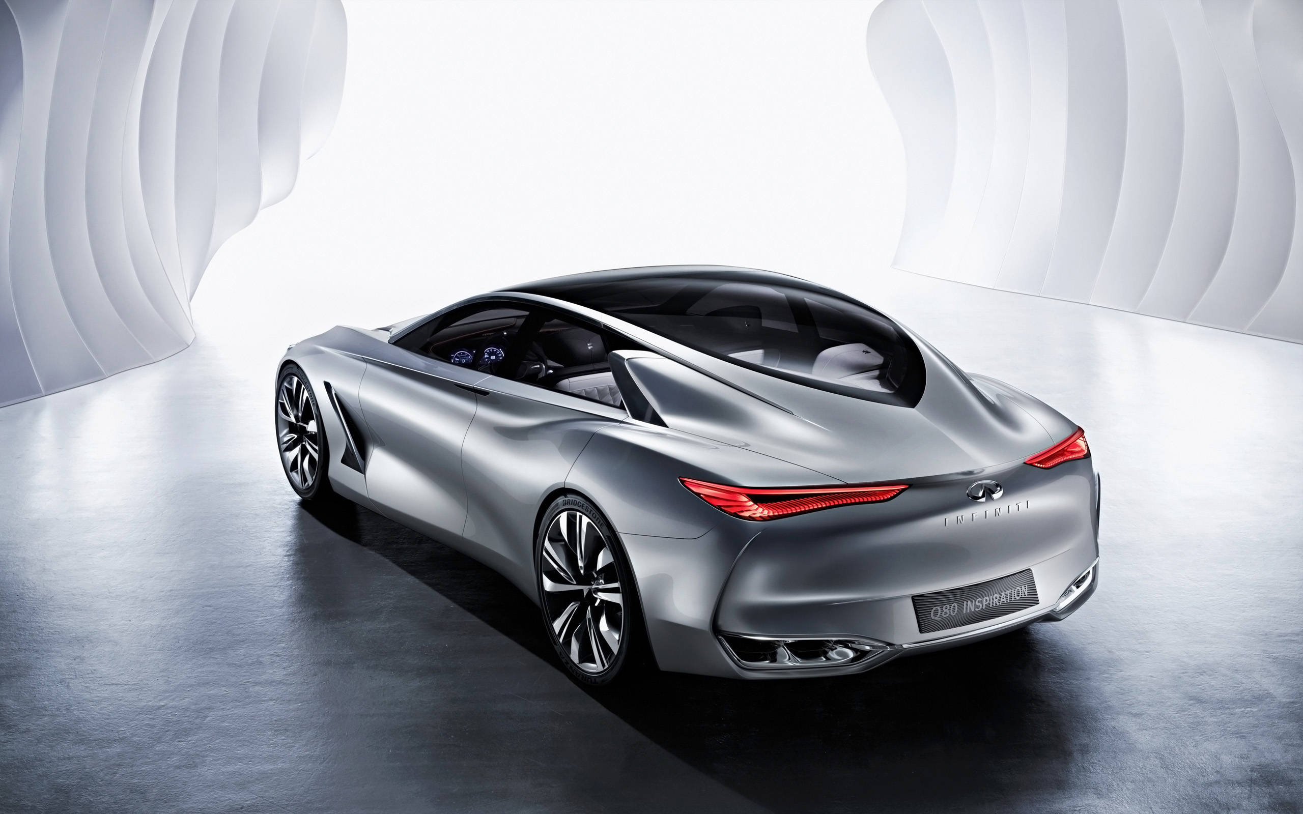 2014 英菲尼迪 Q50 精緻風采 壁紙 — 一輛時尚的銀色Infiniti Q80 Inspiration概念車，帶有發光的紅色尾燈，在未來主義的白色彎曲隧道中展示。