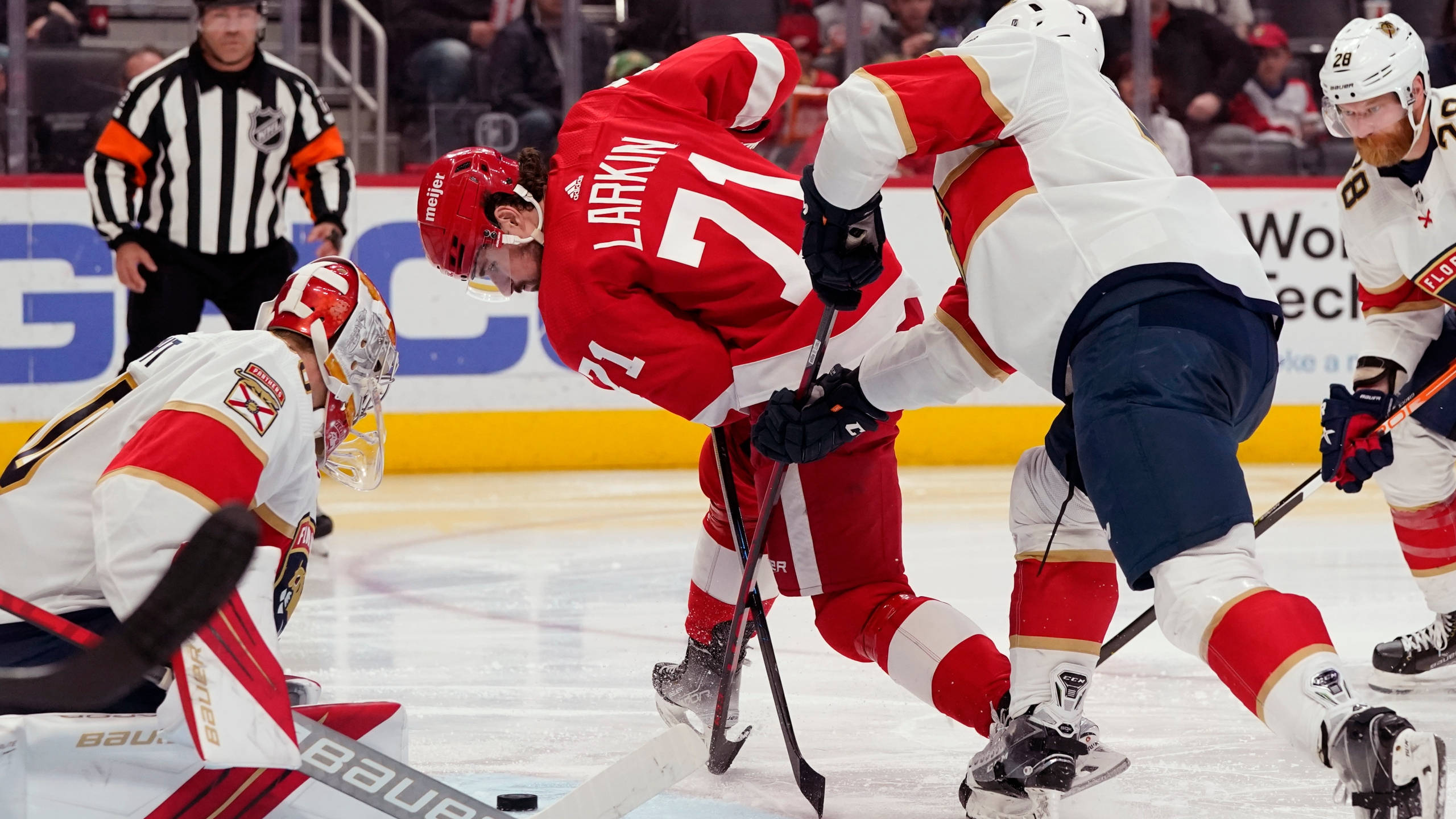 2014年NHL選秀迪倫·拉金 壁紙 — 兩名身穿紅白球衣的冰球運動員在明亮的冰場上激烈爭奪冰球，裁判在旁緊密注視。