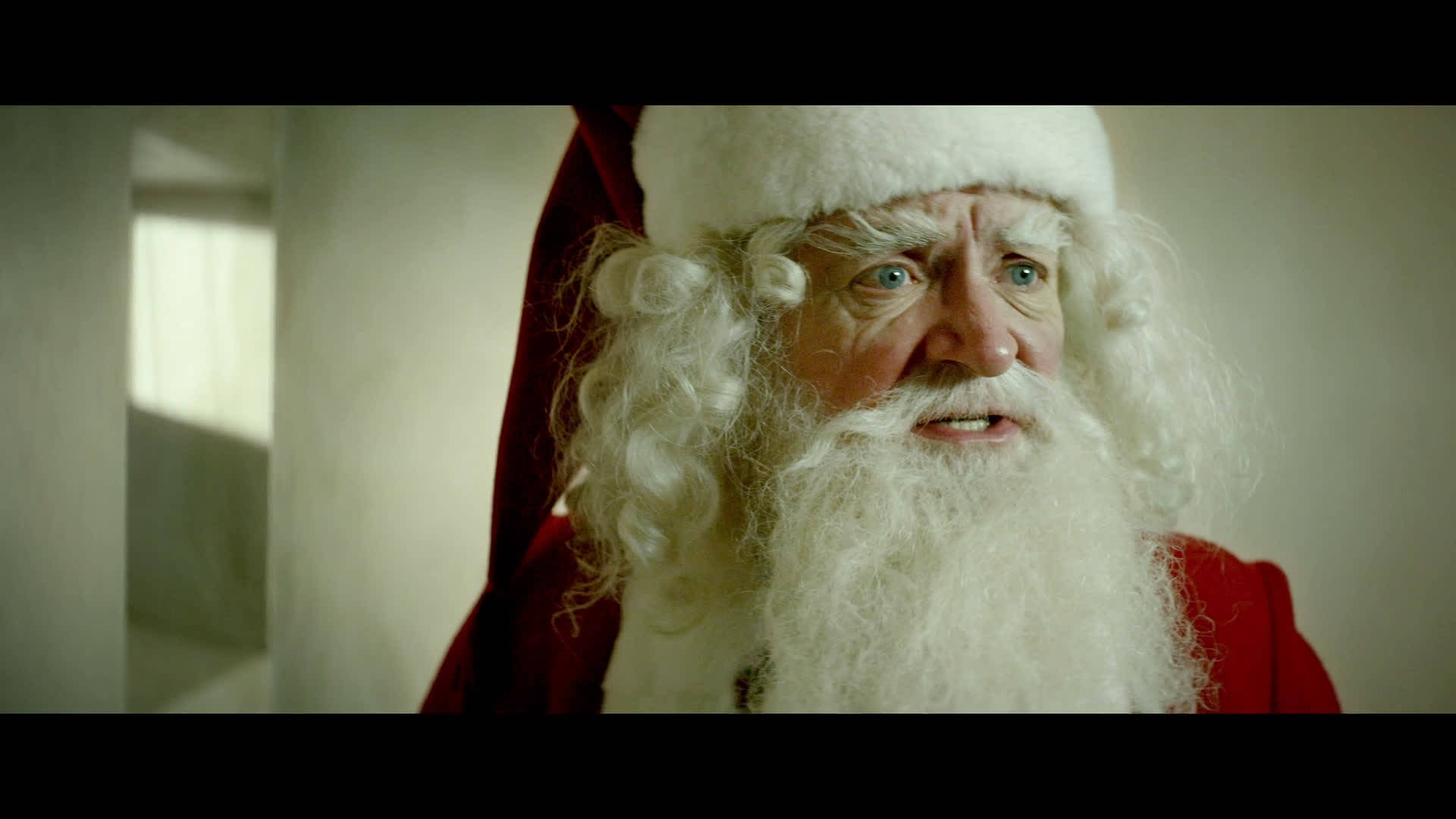 2014年電影《Get Santa》劇照：吉姆·布勞德本特飾演聖誕老人 壁紙 — 特寫一個逼真的聖誕老人，長長的白鬍子和紅色西裝，直視鏡頭。