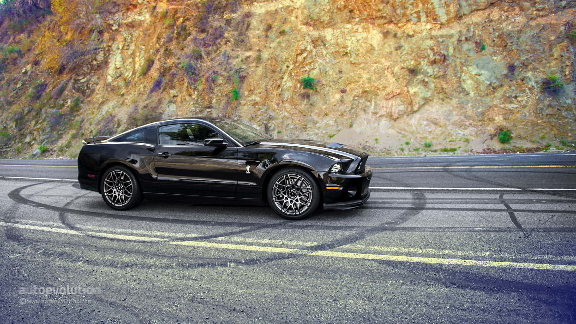 2014款Shelby GT500福特野馬車 壁紙 — 一輛黑色福特野馬Shelby GT500在蜿蜒的山路上進行燒胎表演，背景是崎嶇的懸崖峭壁。