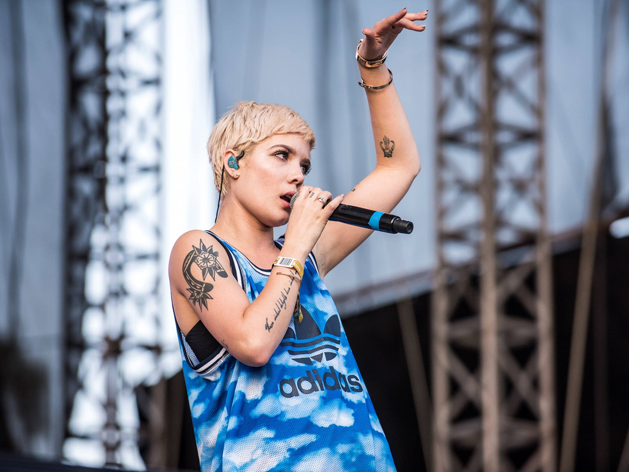 2015 年 Halsey 在墨西哥曬太陽 壁紙 — 一位金髮紋身歌手穿著藍色Adidas背心在舞台上熱情表演。